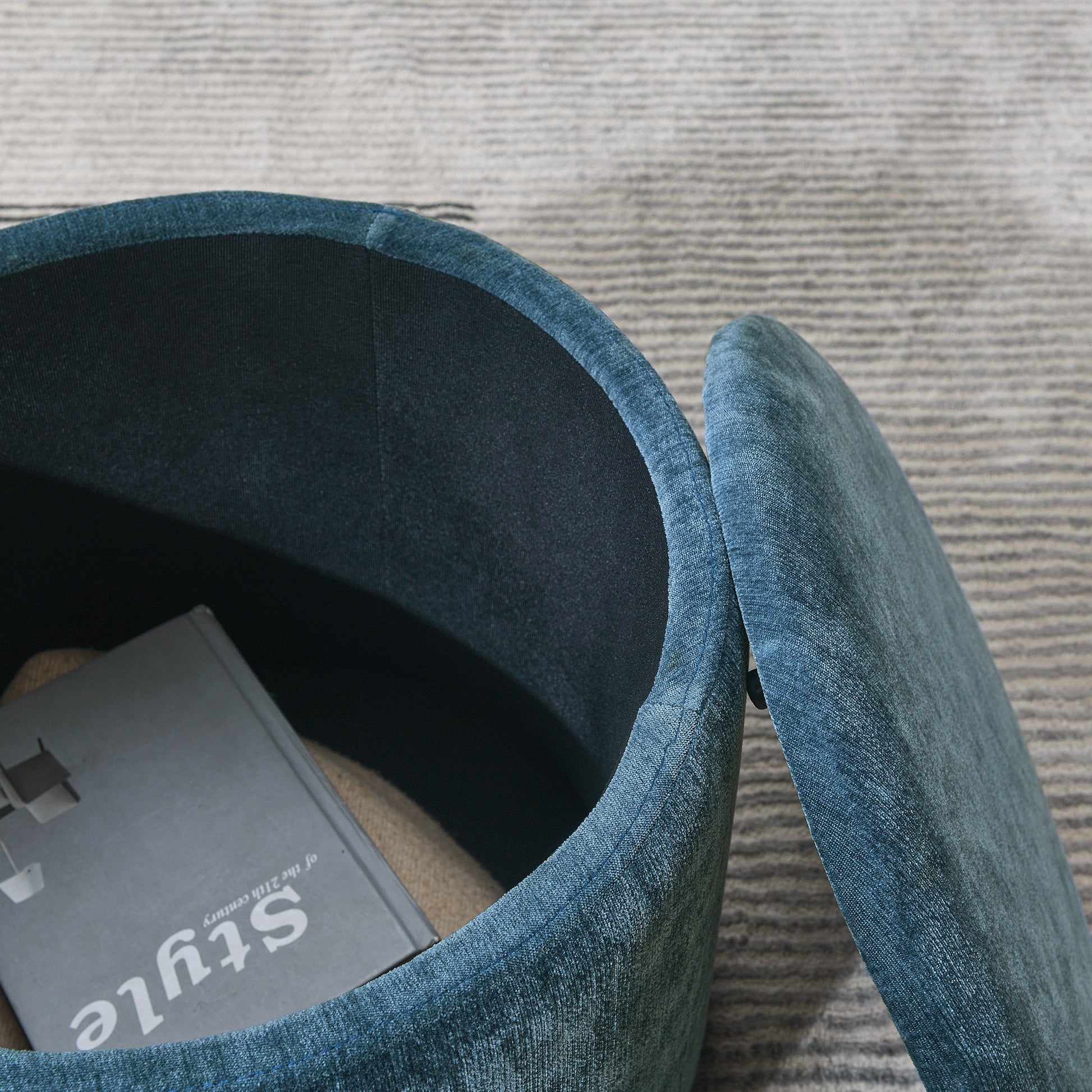 Teal velvet storage ottoman with open lid revealing book