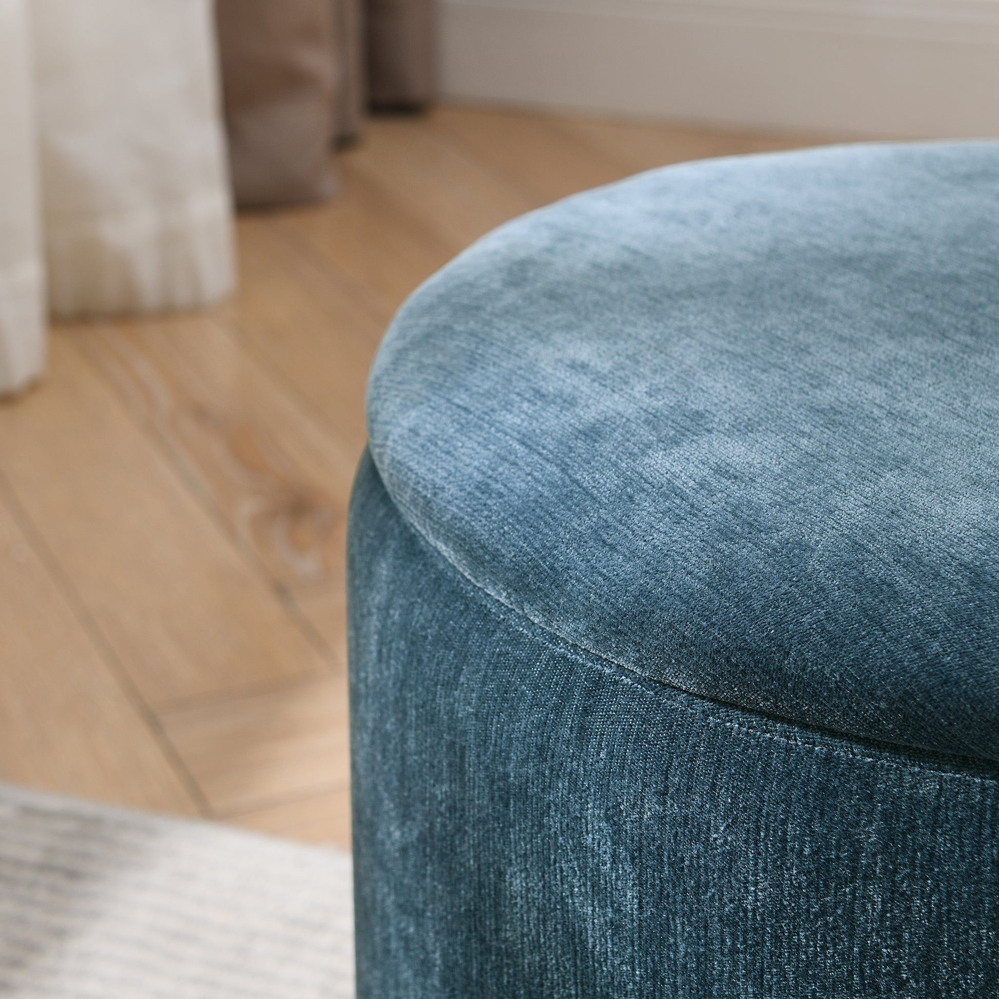 Plush teal velvet ottoman with a curved top perfect for adding a touch of comfort