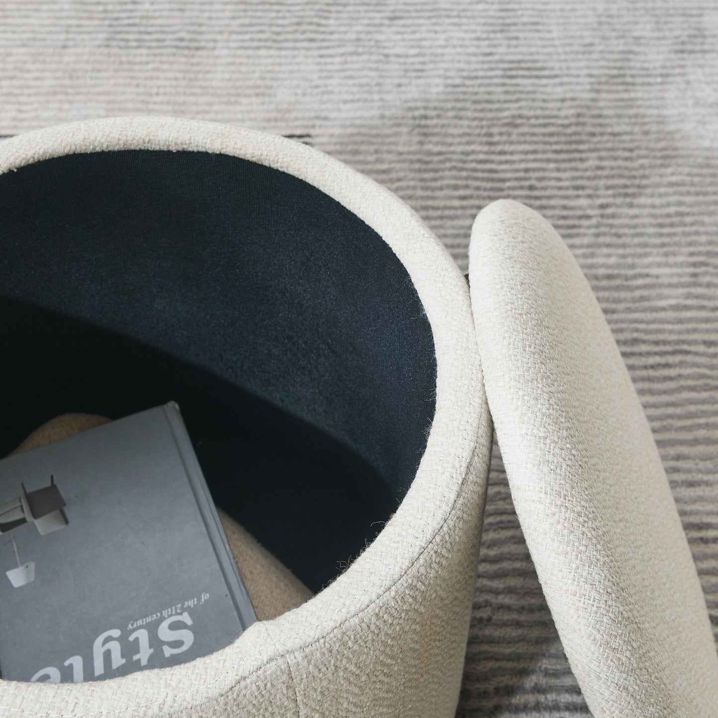 Cream boucle ottoman with storage featuring a dark interior and a style book