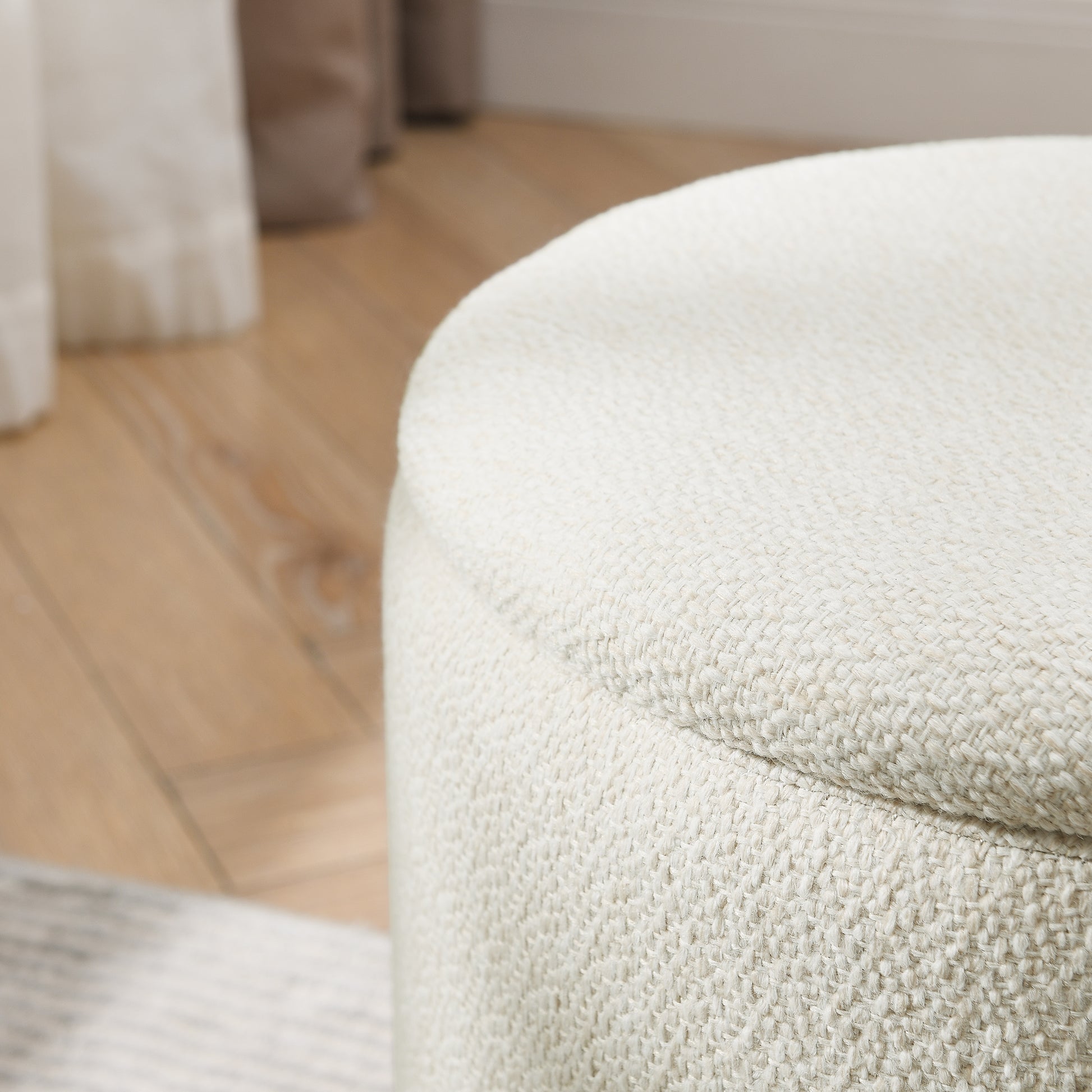 Cream textured fabric ottoman with a rounded top perfect for a living room accent