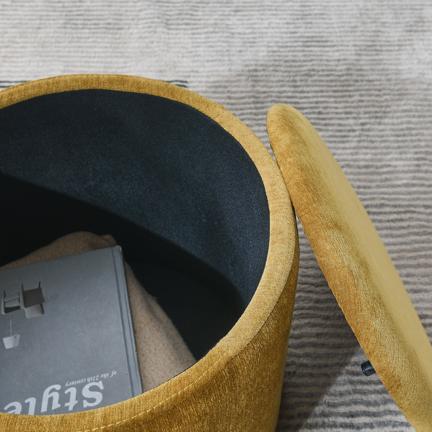 Mustard velvet storage ottoman with open lid revealing dark interior and book