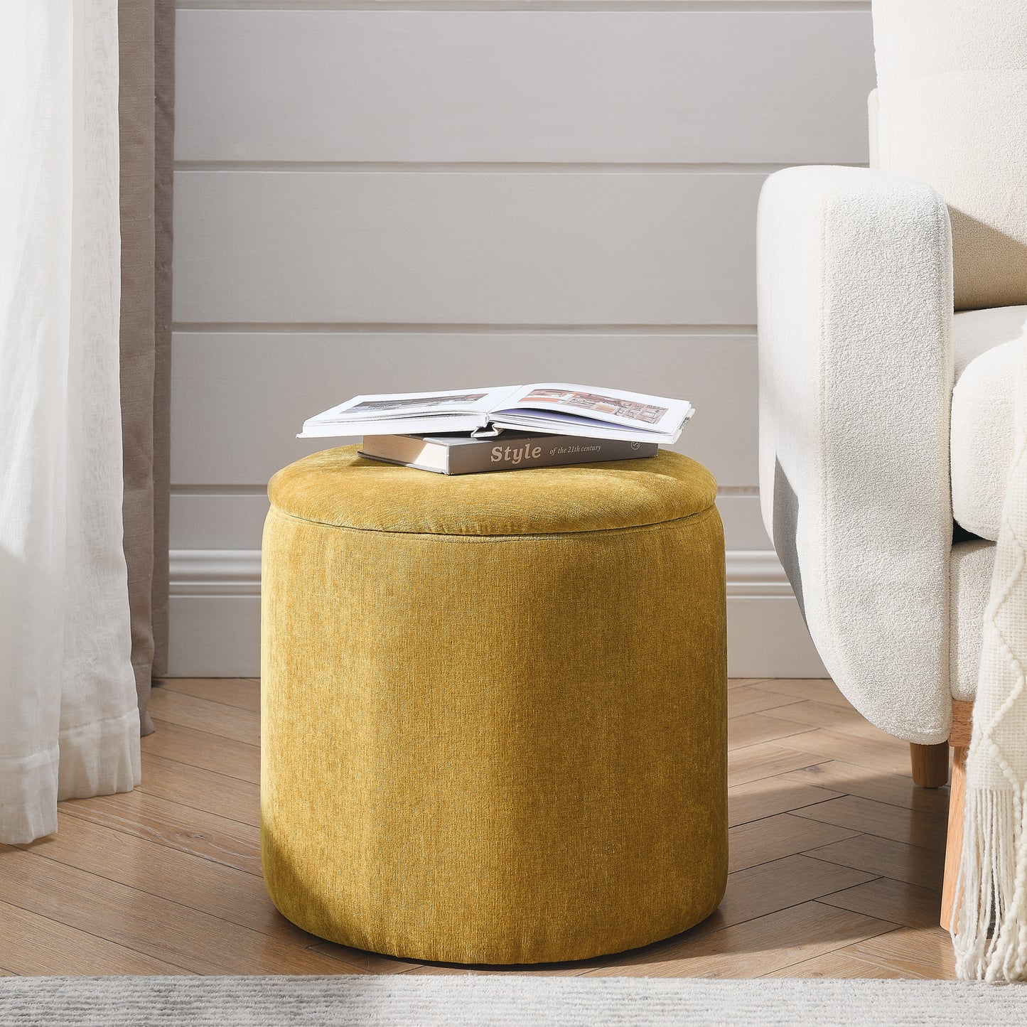 Round mustard yellow storage ottoman with upholstered fabric and a book on top