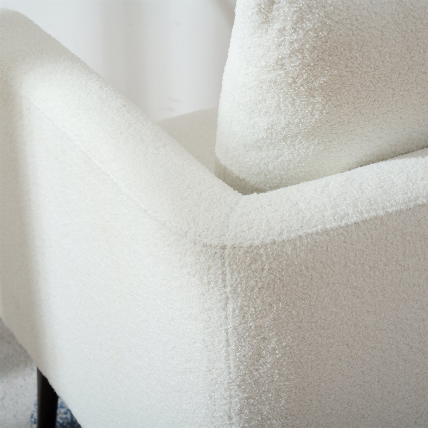 Closeup of a plush white boucle fabric armchair showcasing its textured upholstery and comfortable design