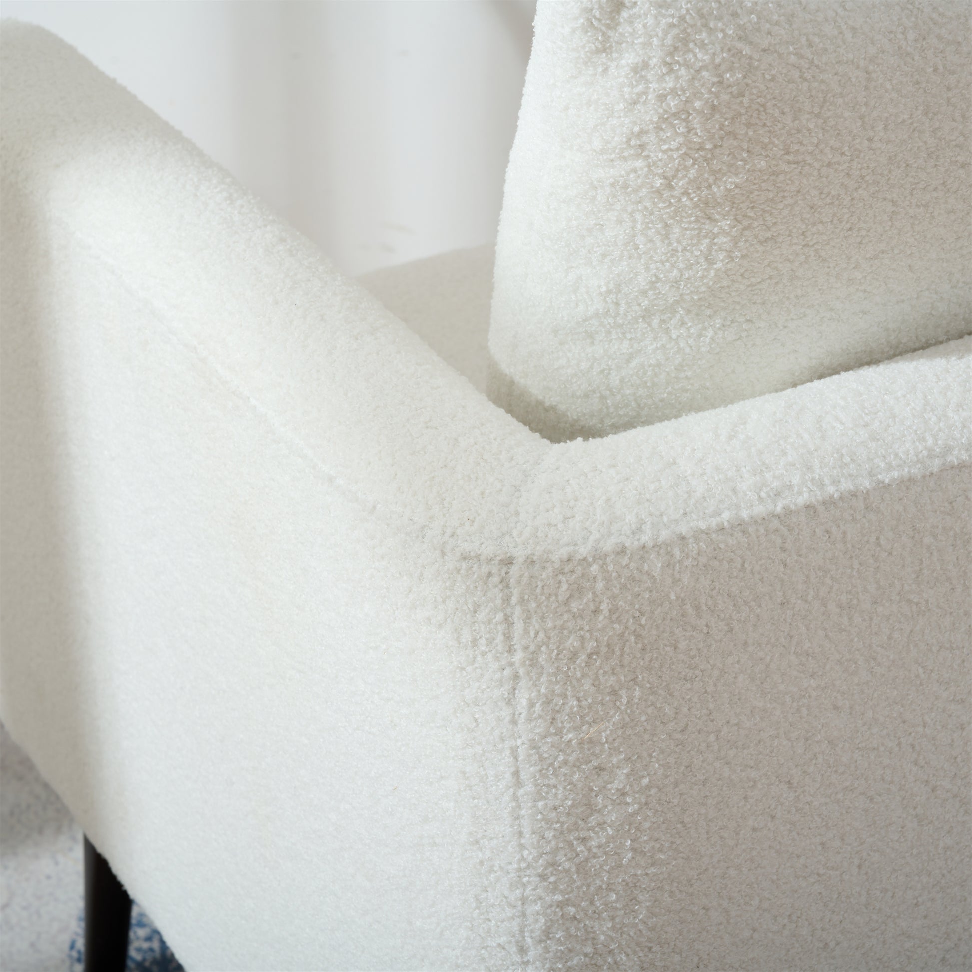 Closeup of a plush white boucle fabric armchair showcasing its textured upholstery and comfortable design