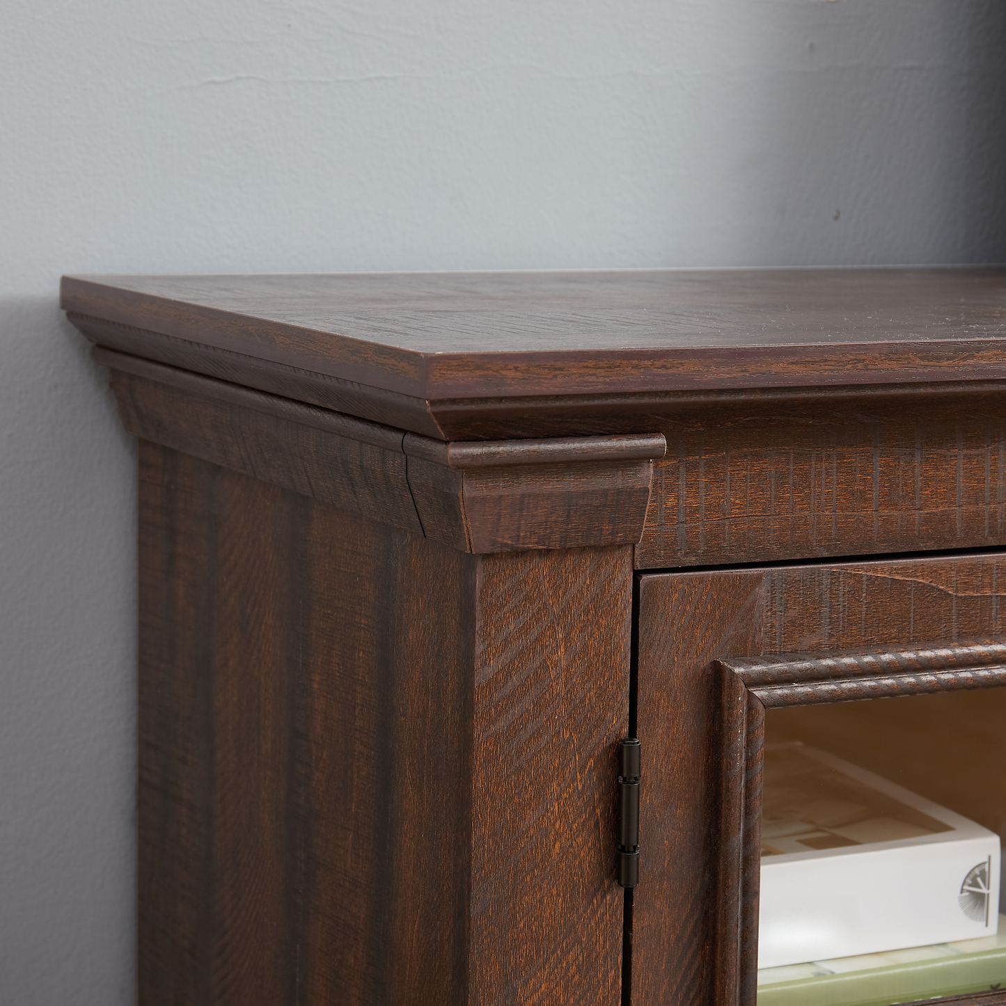 Detail of a dark wood cabinet with carved trim and textured finish