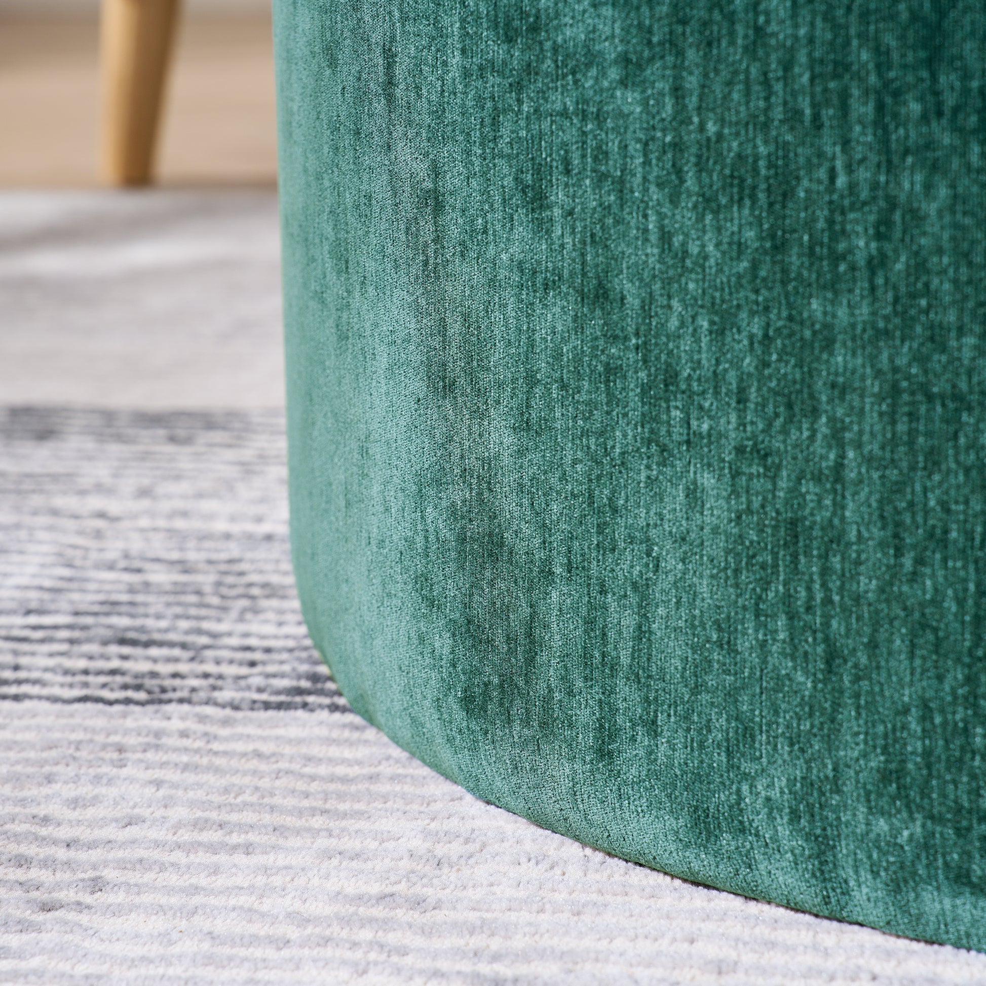 Closeup of a deep green velvet ottoman with a textured fabric surface