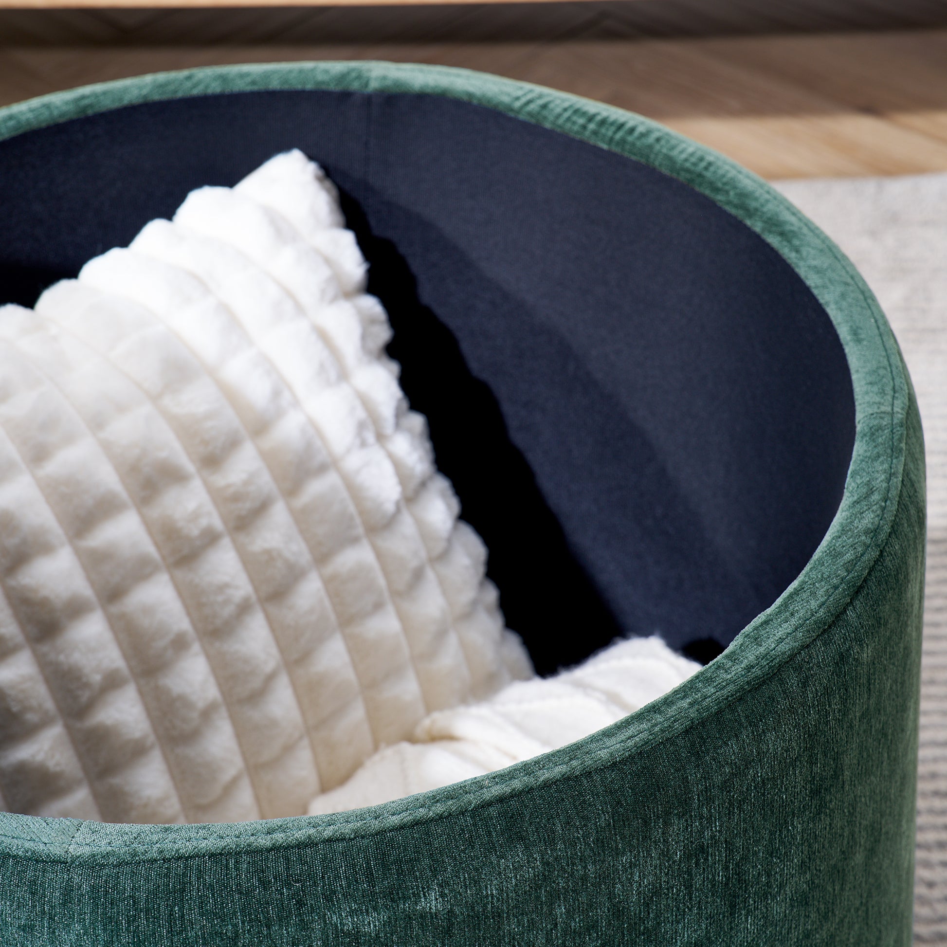 Deep emerald green velvet ottoman with plush white cushion inside