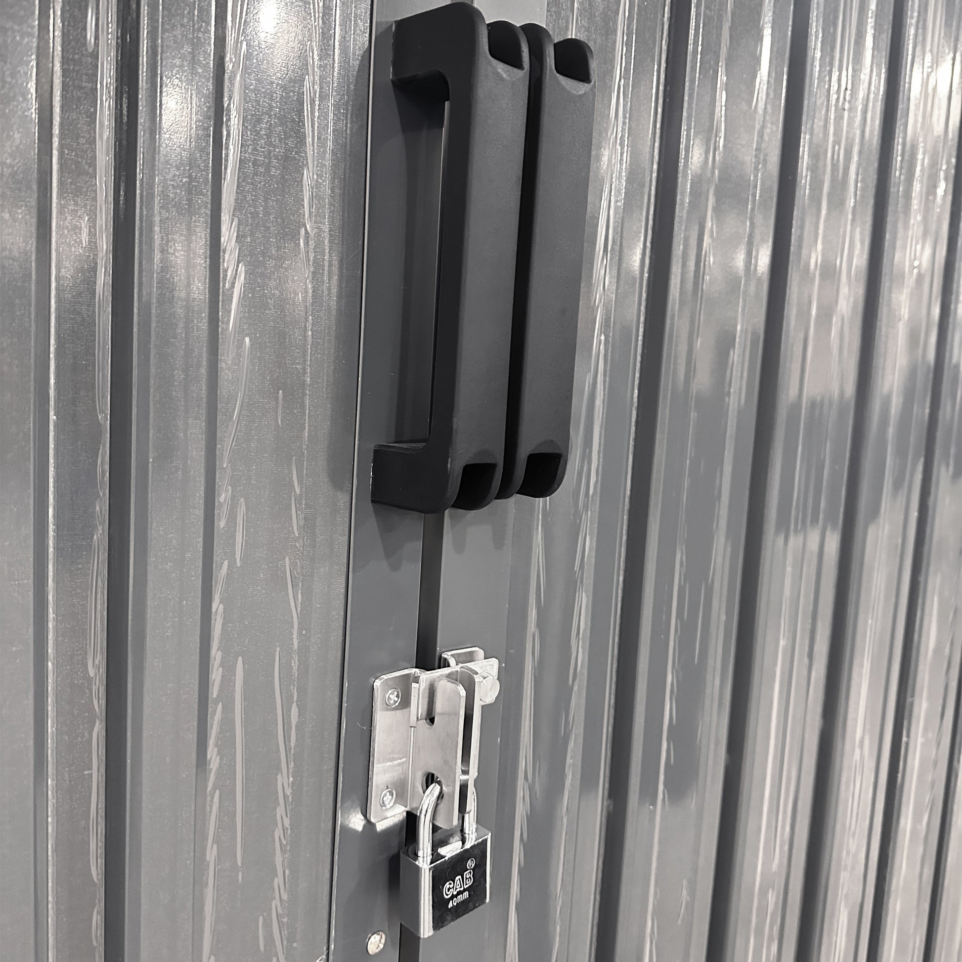Dark gray corrugated metal shed door with black handle and silver padlock