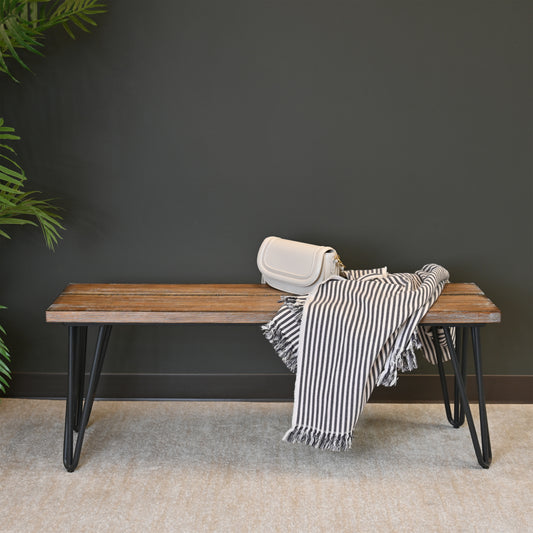 Rustic wooden bench with hairpin legs displaying a white handbag and striped throw