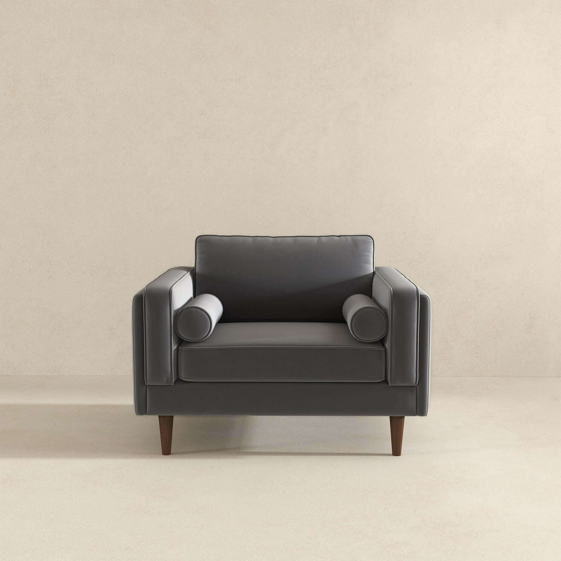 Modern grey velvet armchair with tufted sides and round bolster pillows