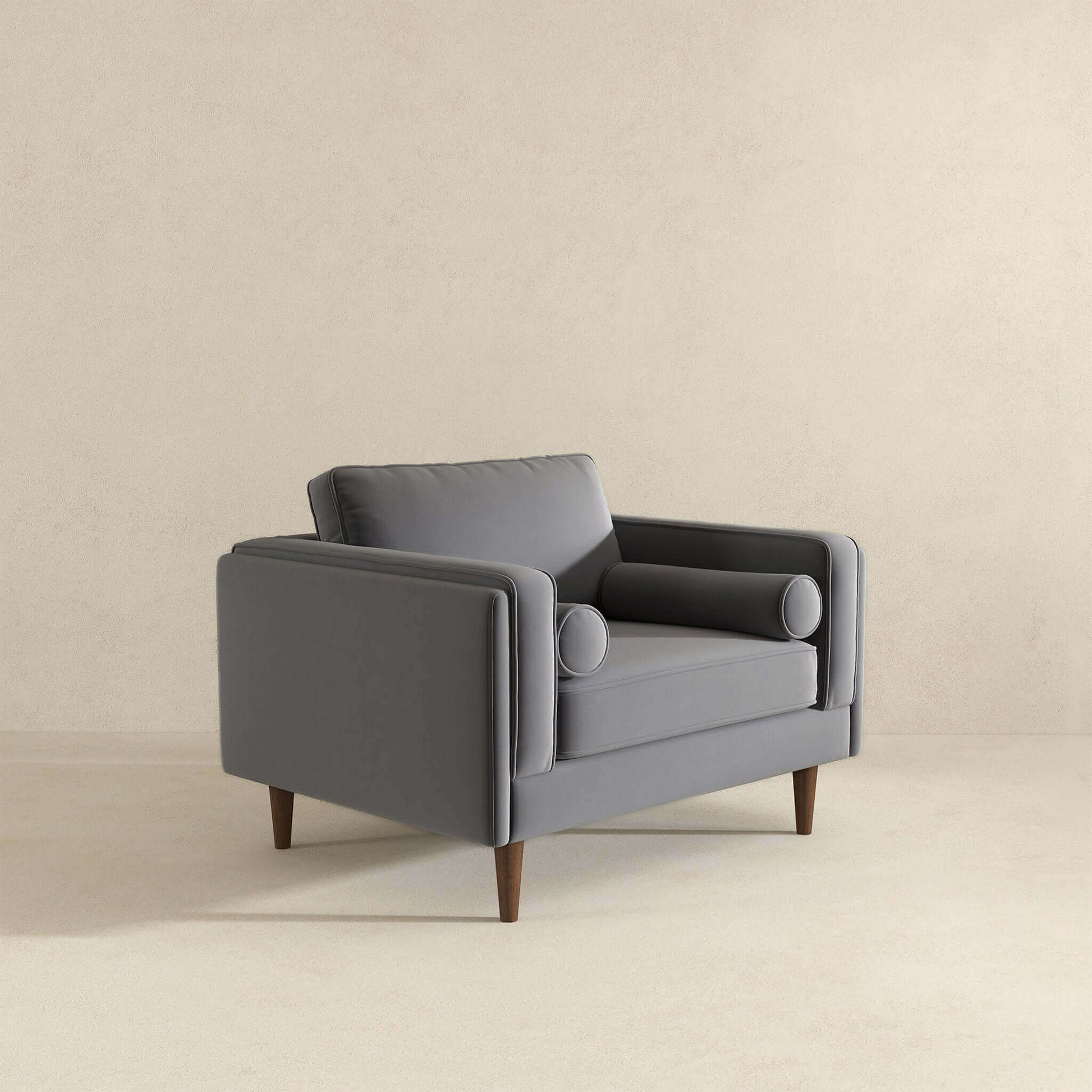 Modern grey velvet armchair with wooden legs and bolster pillow