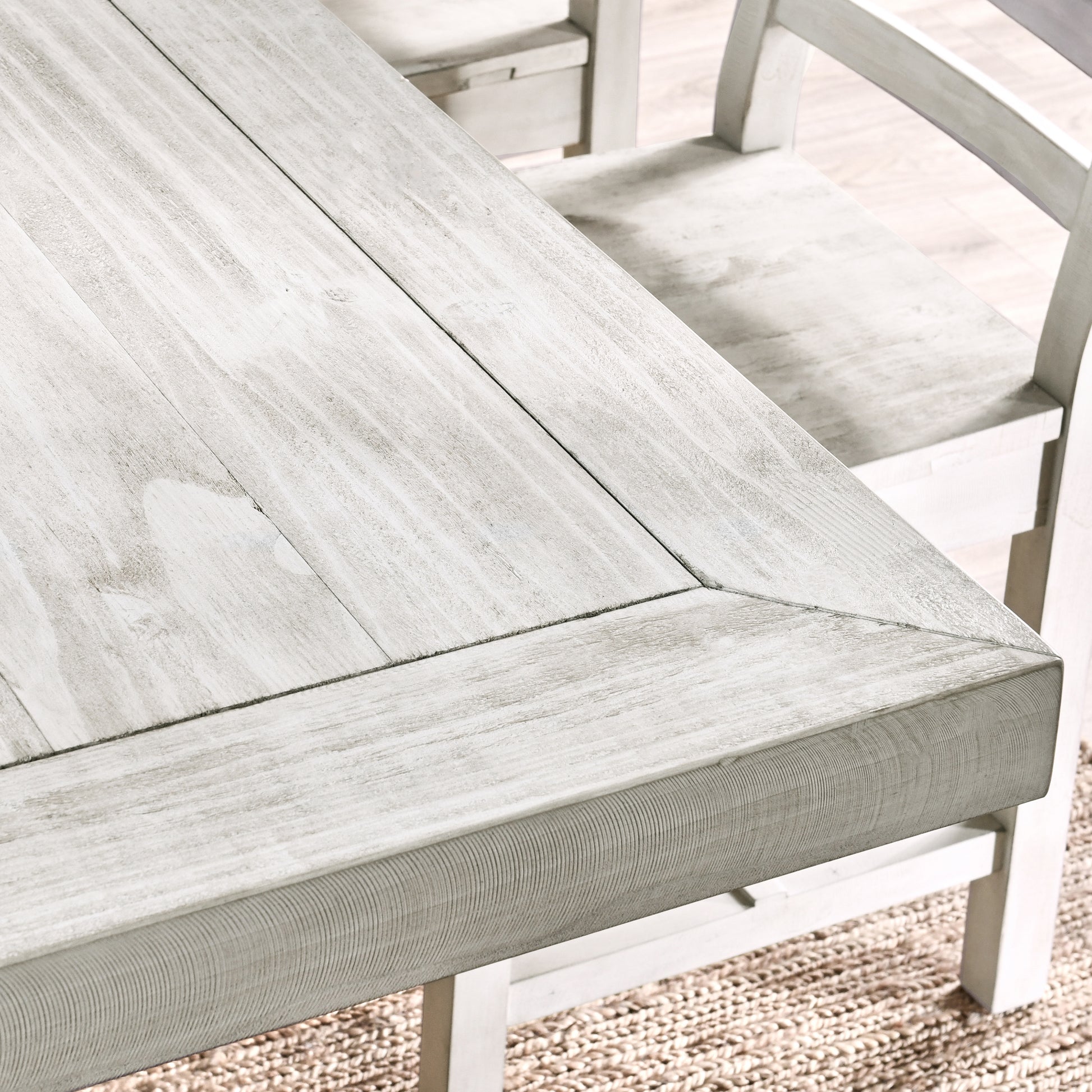 Distressed white wood dining table with planked surface and bevelled edge