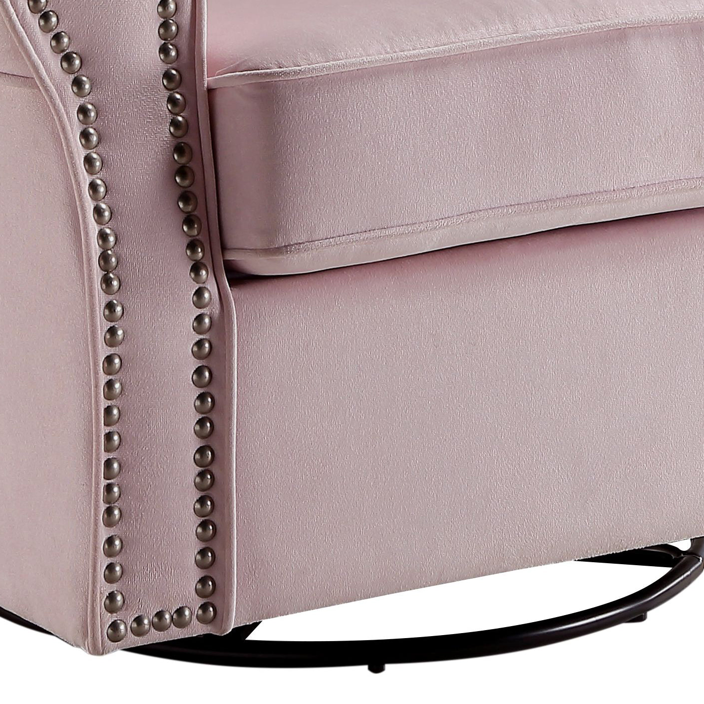 Closeup of a plush pink velvet armchair with silver nailhead trim and a black swivel base