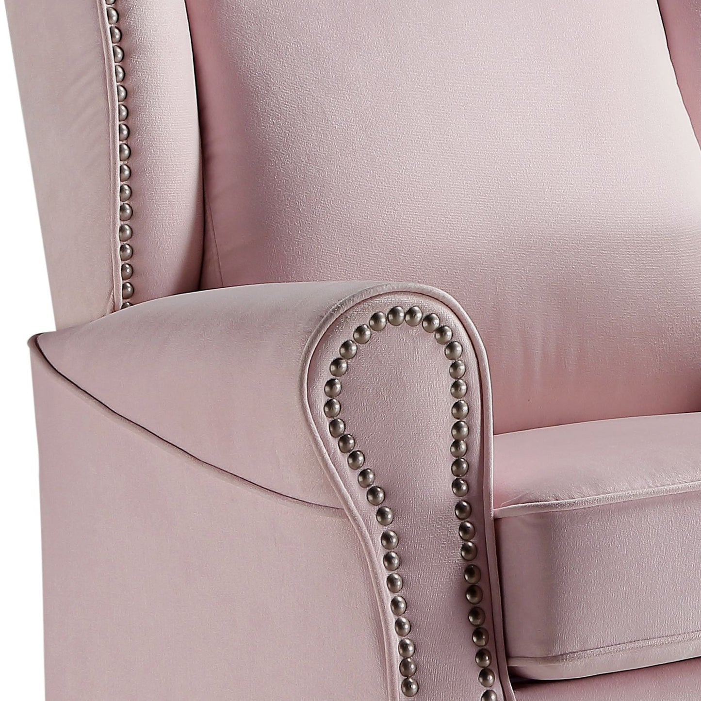 Closeup of a plush pink velvet accent chair with ornate nailhead trim along the armrest and wingback