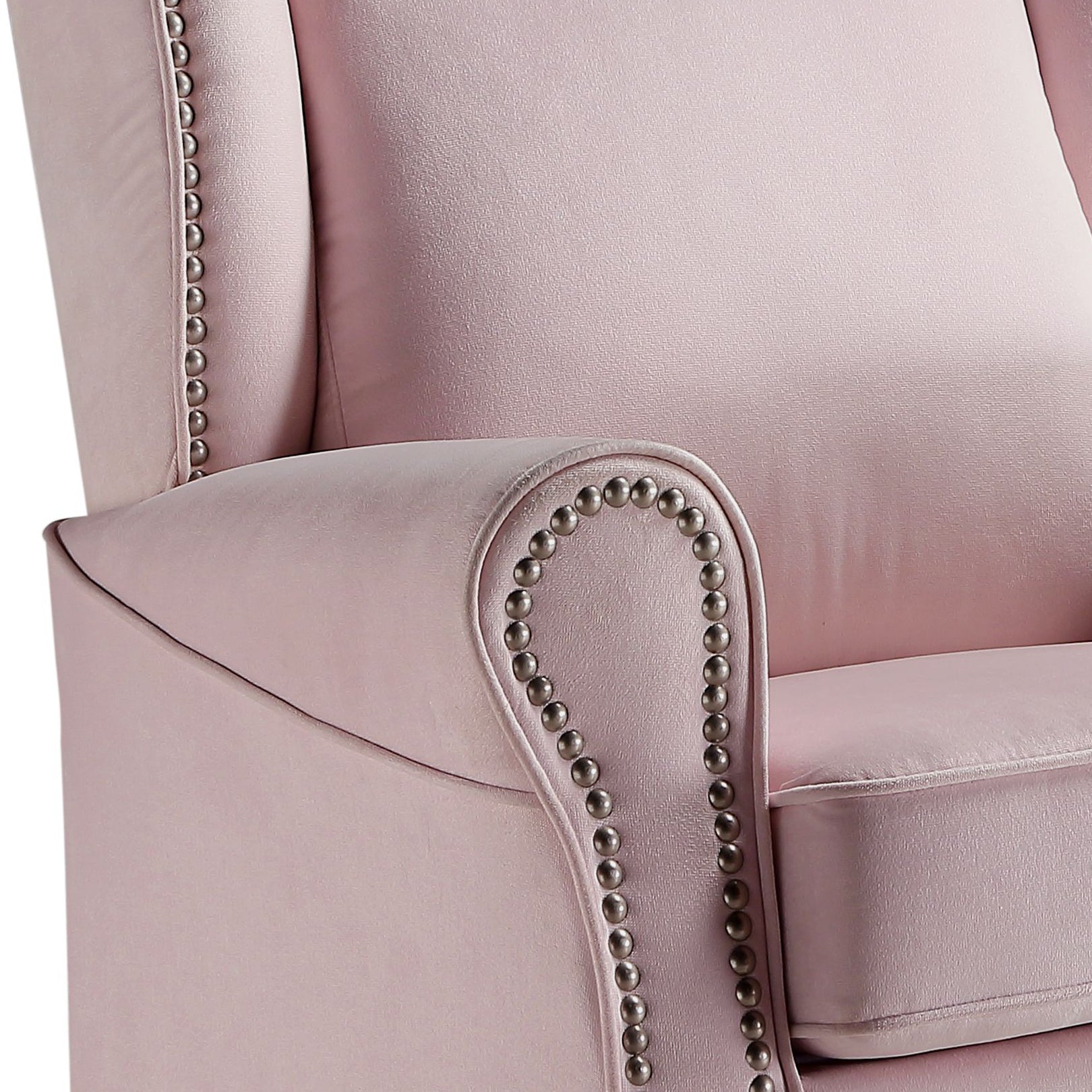 Closeup of a plush pink velvet accent chair with ornate nailhead trim along the armrest and wingback