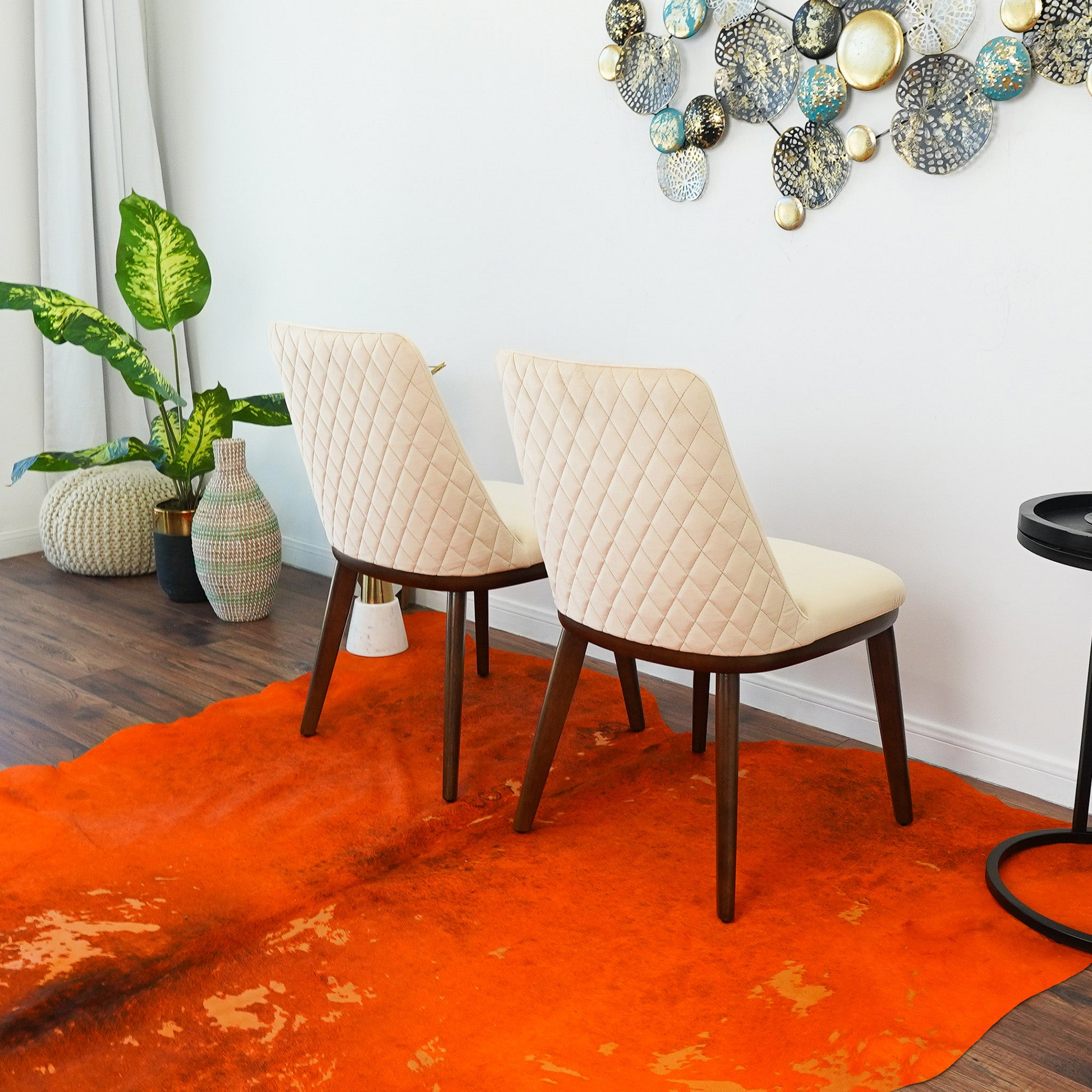 Cream quilted accent chair with dark wood legs on an orange cowhide rug