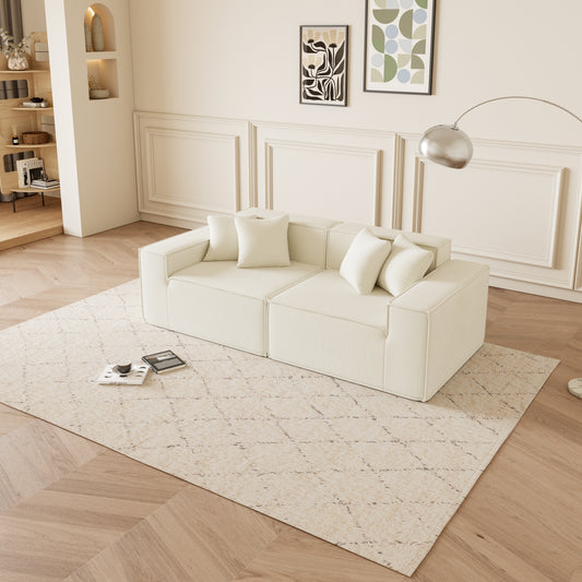 Cream sectional sofa with four matching plush pillows on a patterned rug