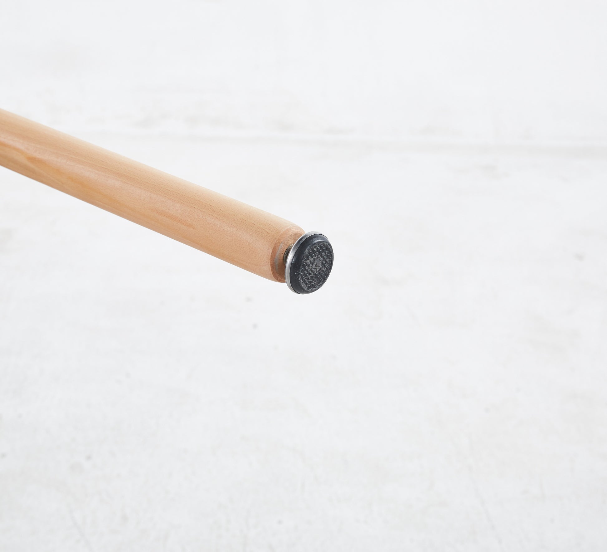 Closeup of a natural wood chair leg with a black protective foot