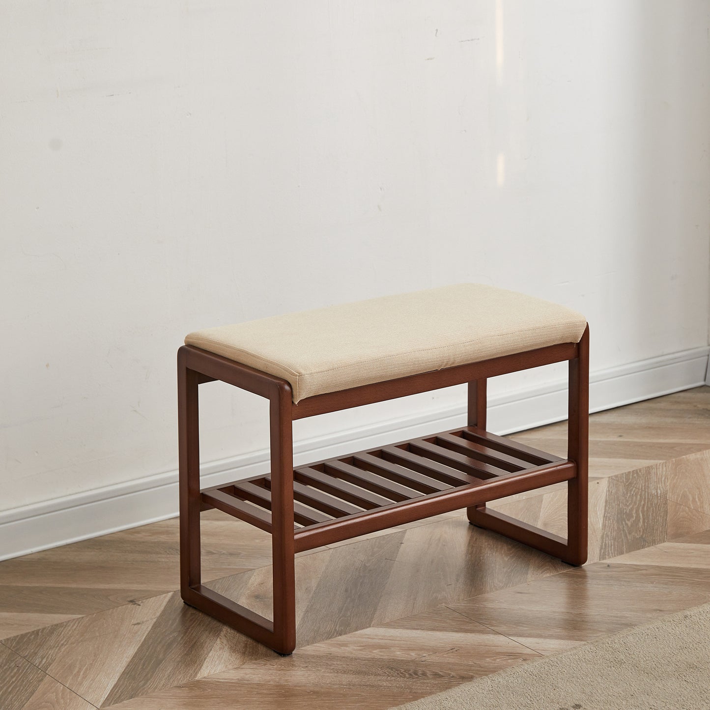 Dark wood entryway bench with cushioned seat and slatted lower shelf for shoe storage