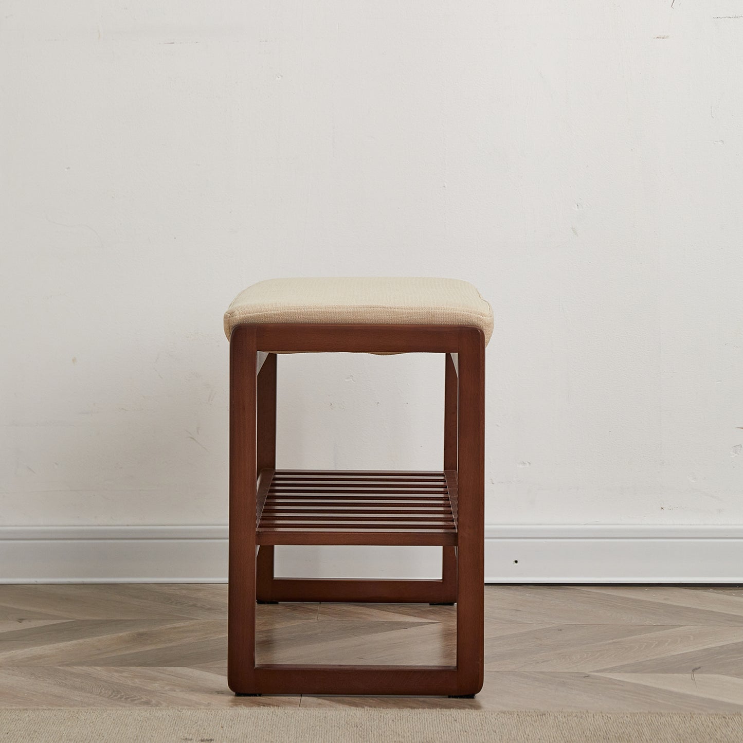 A dark wood entryway bench with a beige fabric seat and slatted lower shelf