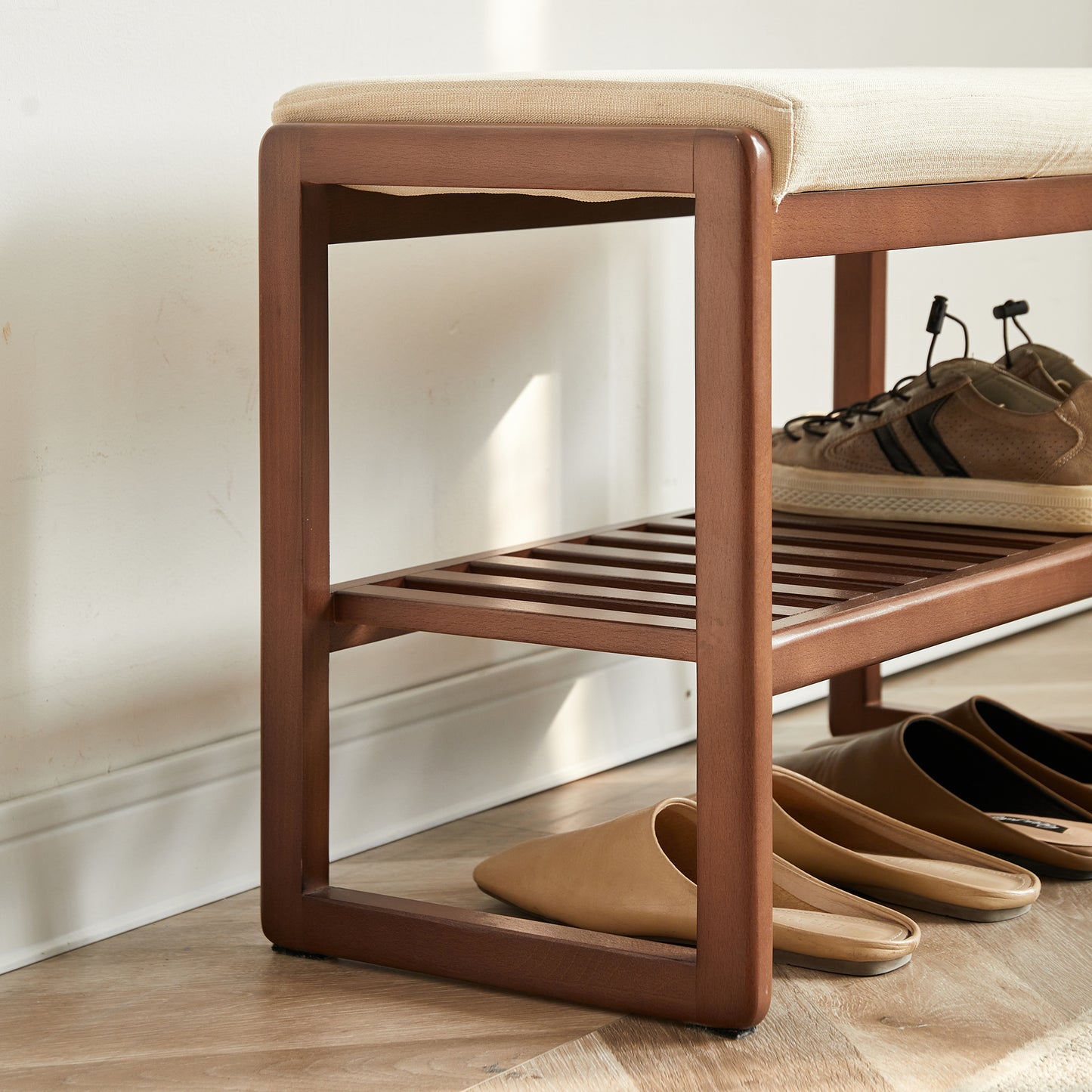 Wooden shoe bench with cushioned seat holds brown sneakers and tan slipon shoes