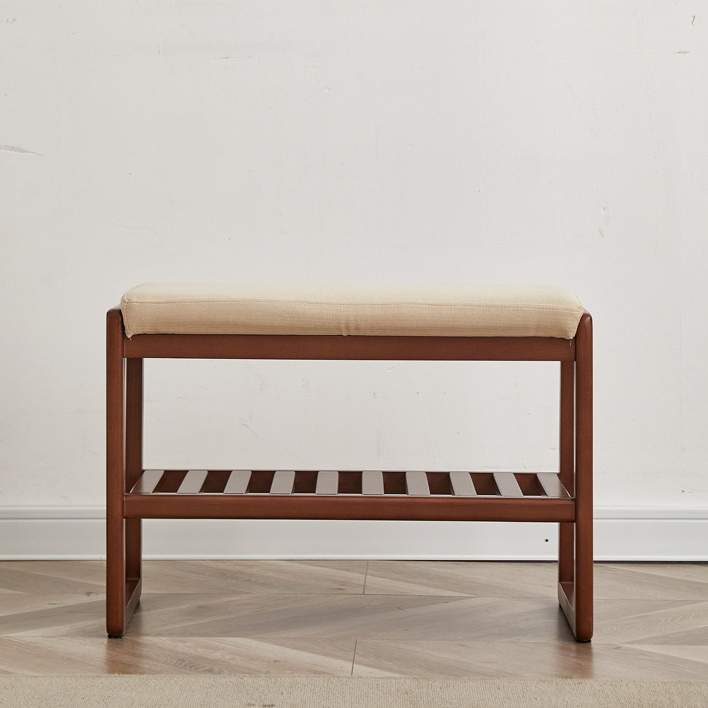 Wooden shoe bench with beige upholstered top and slatted lower shelf for entryway storage
