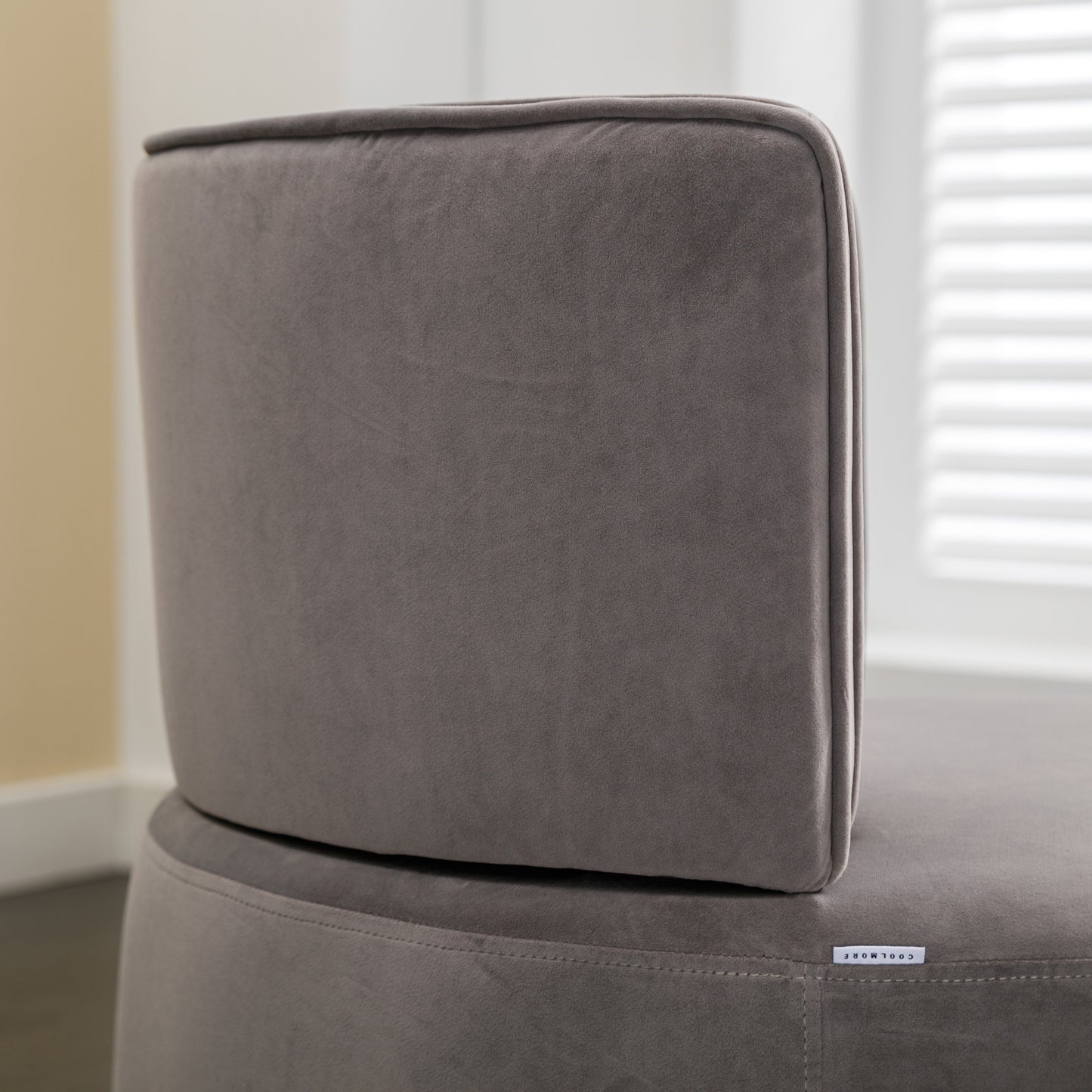 Closeup of a plush grey velvet ottoman with a discreet brand tag