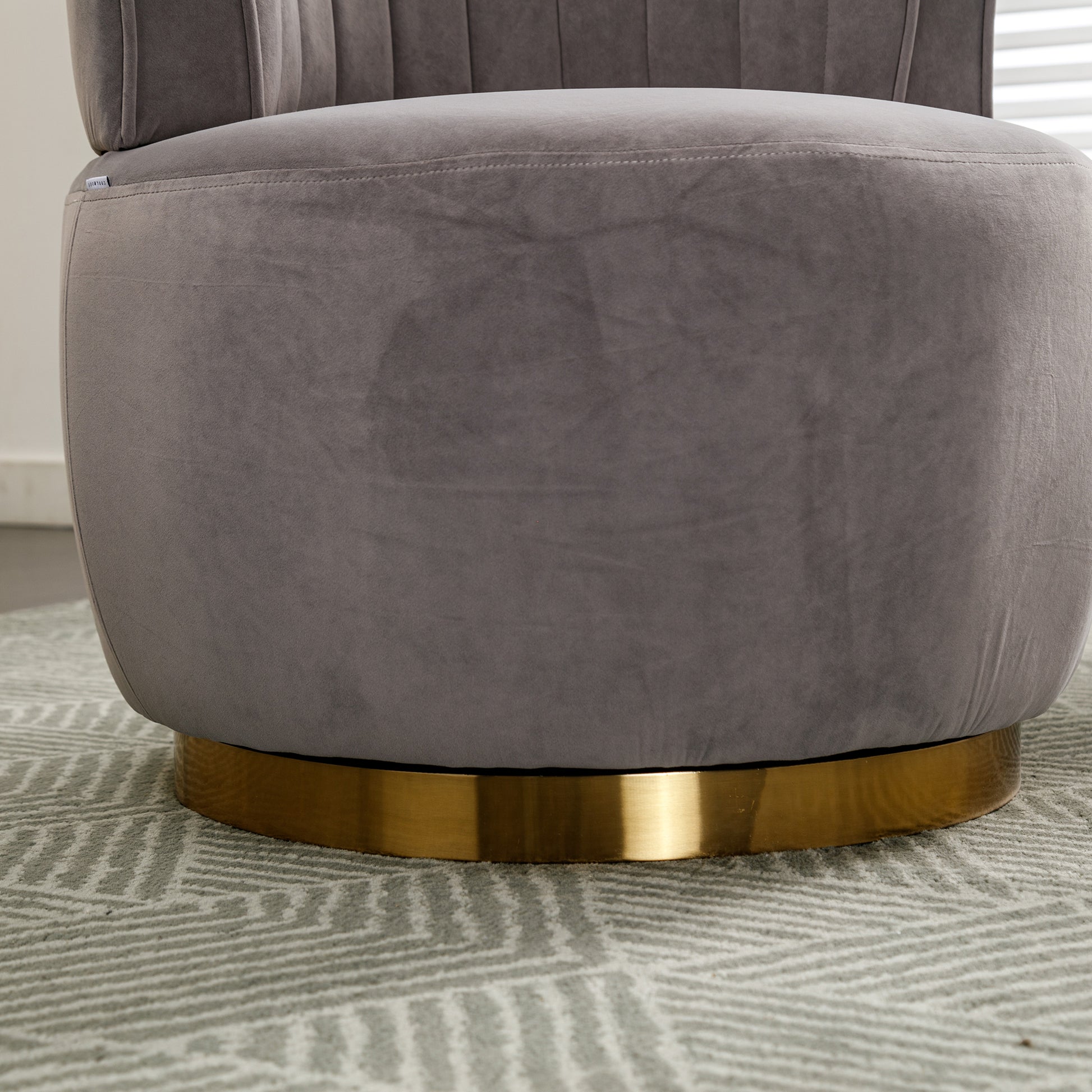 Closeup of a plush grey velvet ottoman with a gilded gold base perfect for footrest