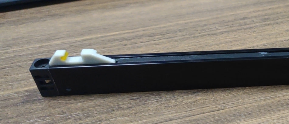 Black track light adapter with white and yellow plastic connector on wooden surface