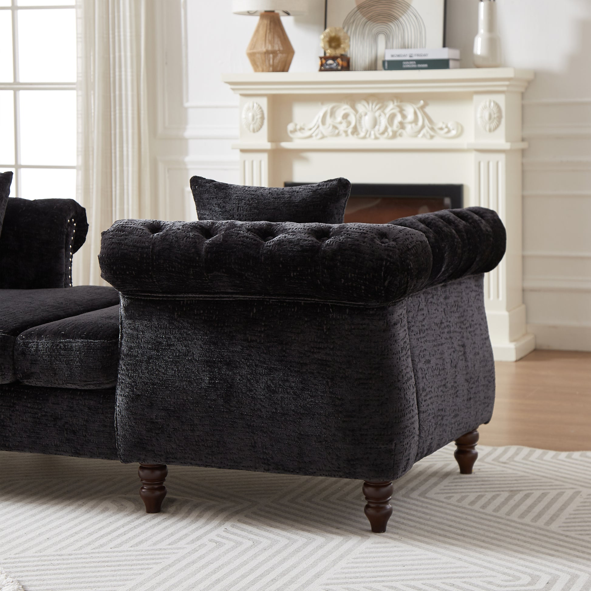 Black tufted velvet sofa with ornate wooden legs and studded armrest detail