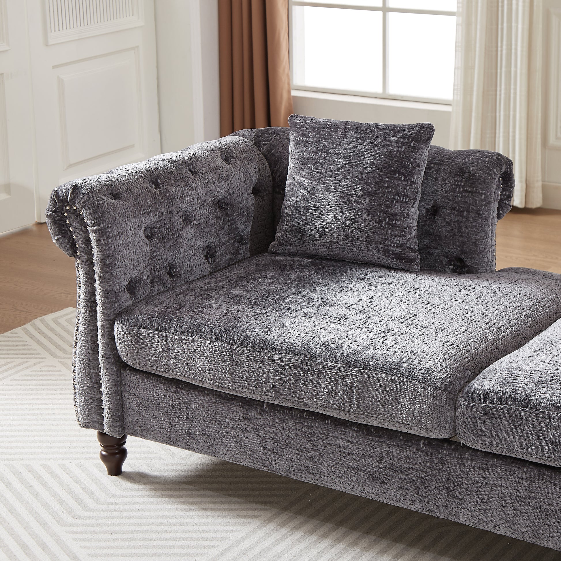 Tufted charcoal grey velvet chaise lounge with ornate details and plush seating