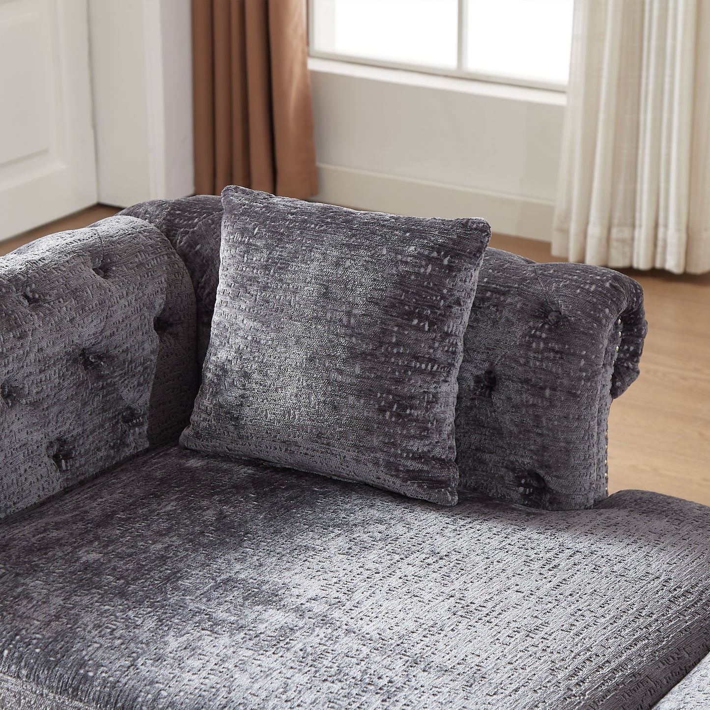 Dark gray textured velvet sofa with tufted details and matching throw pillow