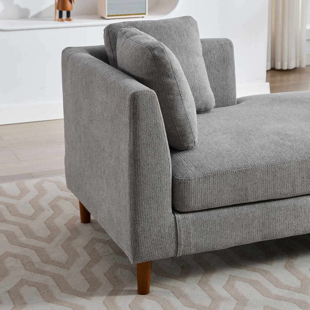 Textured grey fabric chaise lounge with wooden legs and accent pillow