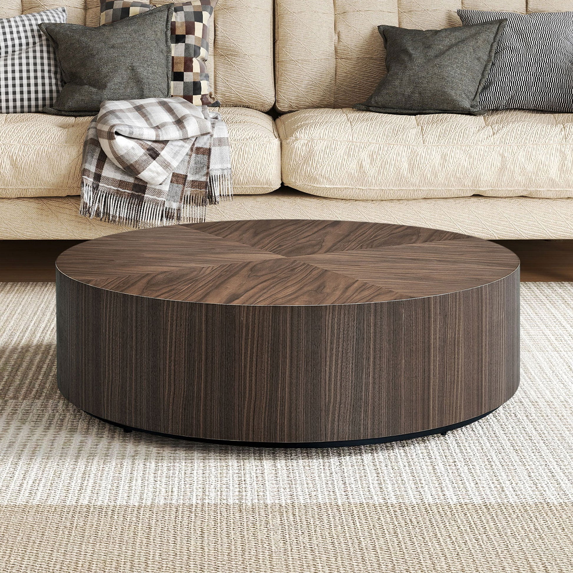 Dark wood round coffee table with a striped base on a textured rug