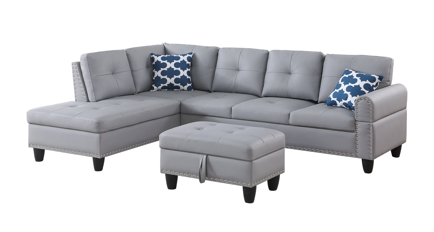 Tufted gray faux leather sectional sofa with silver nailhead trim and blue patterned accent pillows