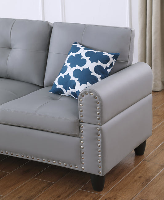Grey tufted faux leather couch with silver nailhead trim detail on armrest