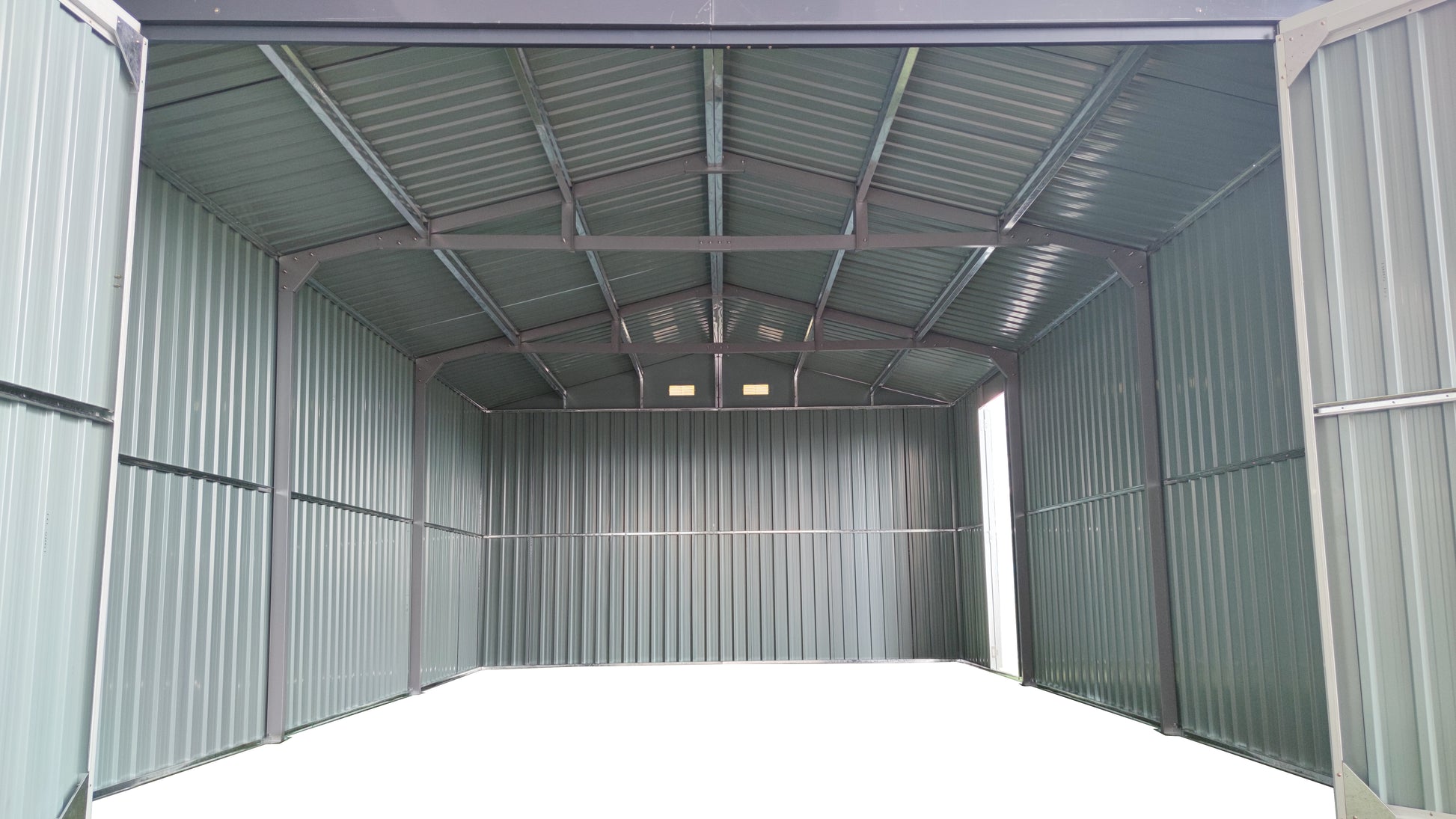 Interior view of a spacious green metal garage with open double doors