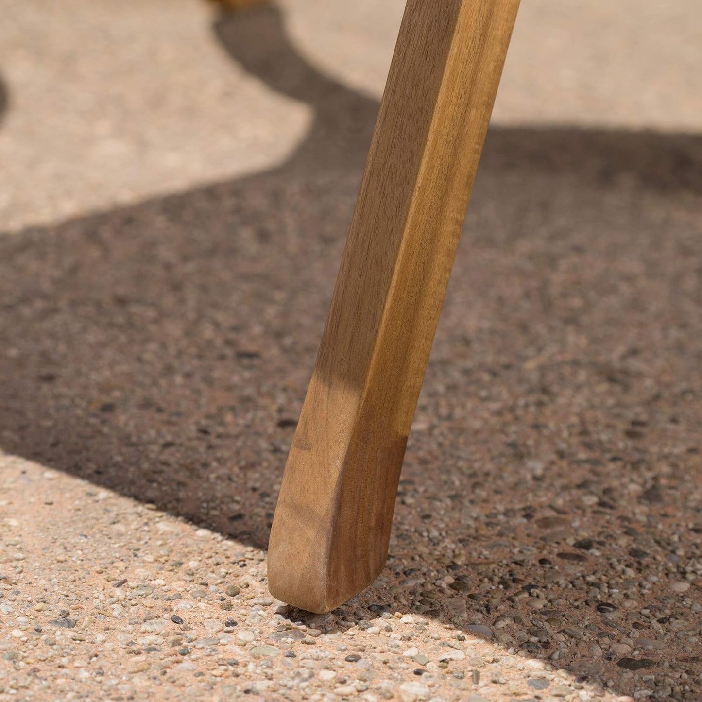 Natural wood chair leg on textured concrete ground