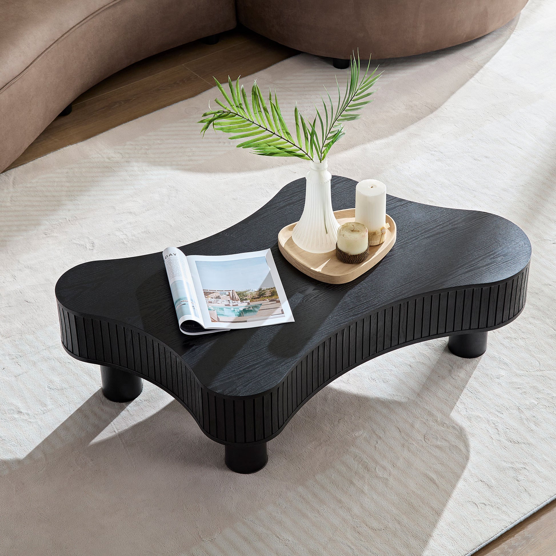 Sculptural black wood coffee table with fluted sides and organic shape