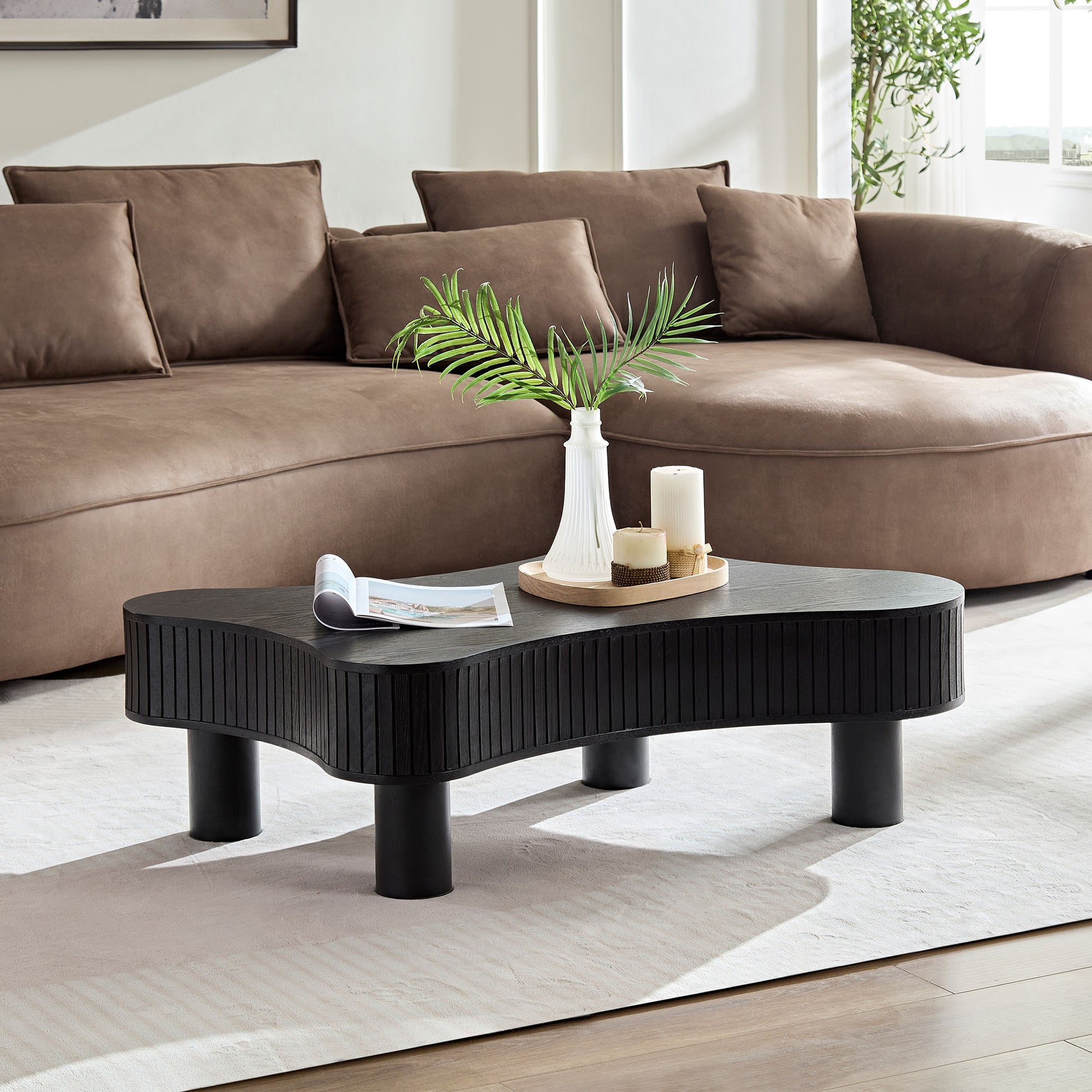 Black wooden wavy coffee table with ribbed detailing and black cylindrical legs