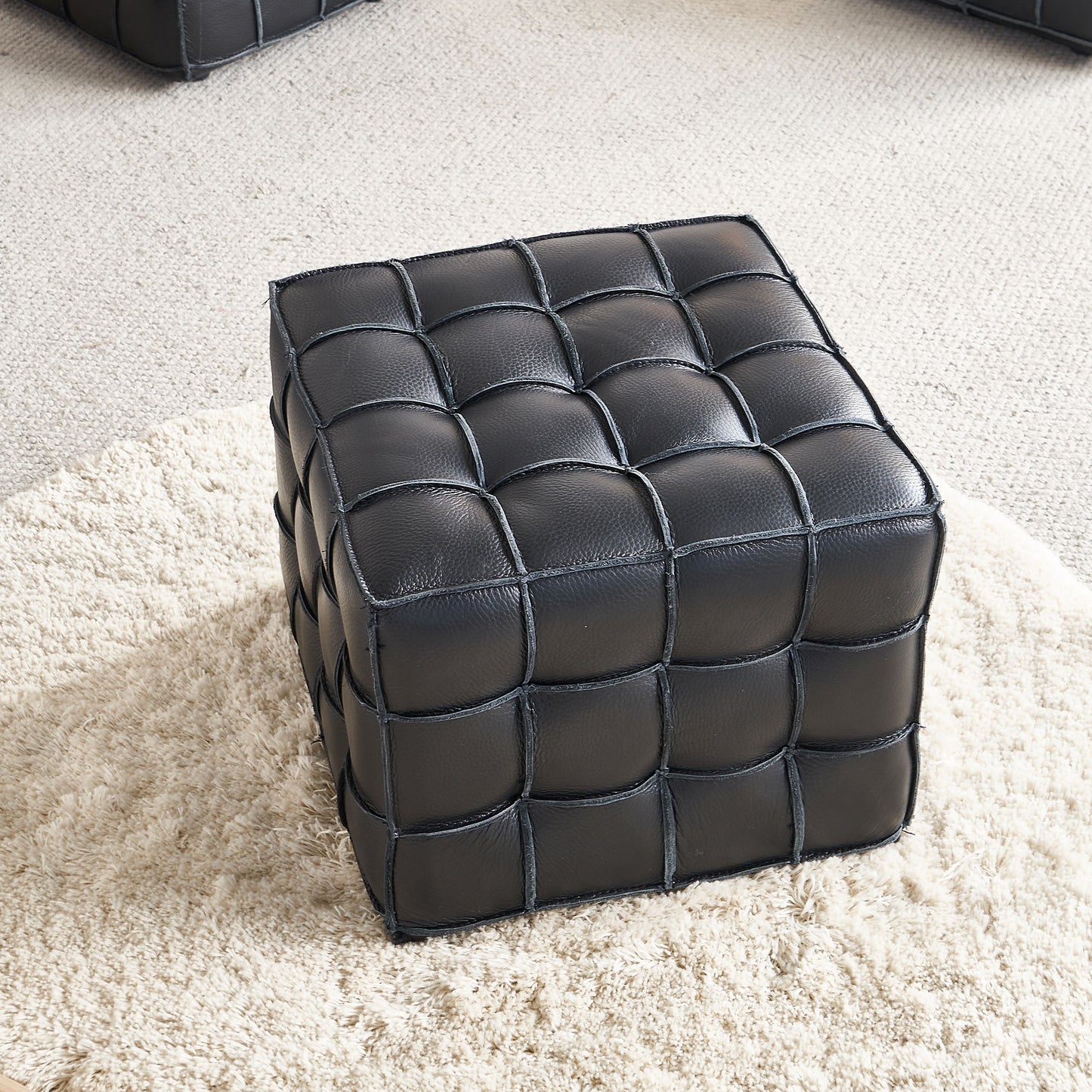 Black leather woven cube ottoman on shag rug