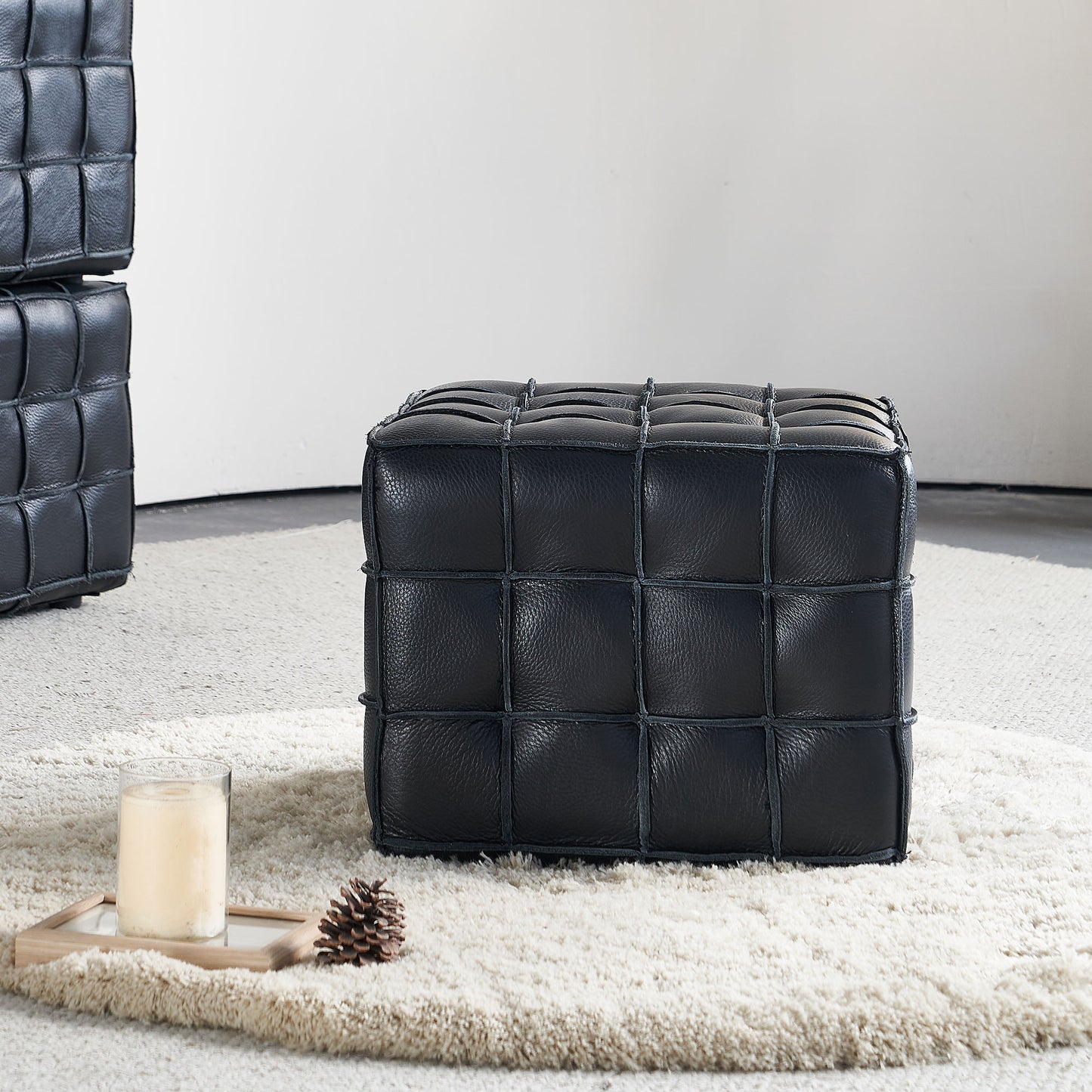 Black tufted leather cube ottoman on a cream shag rug accent seating