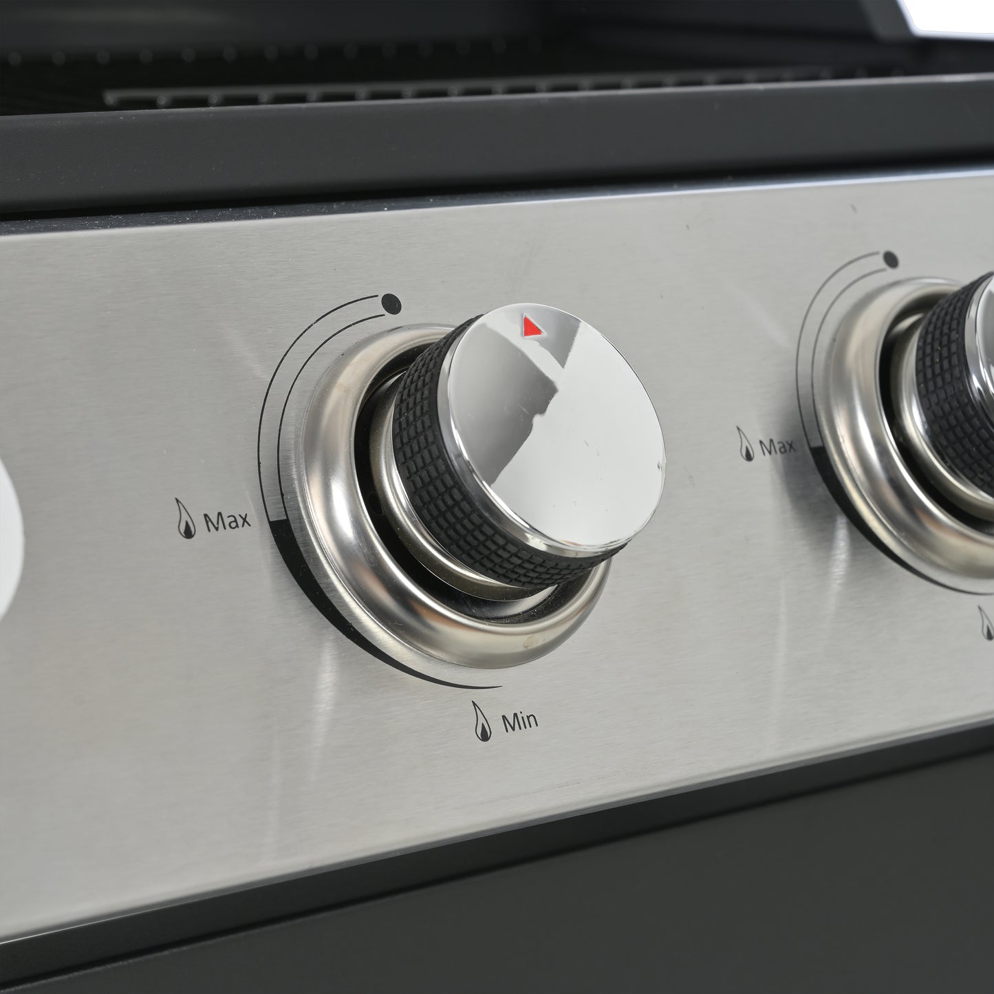 Closeup of a stainless steel grill control knob with red indicator