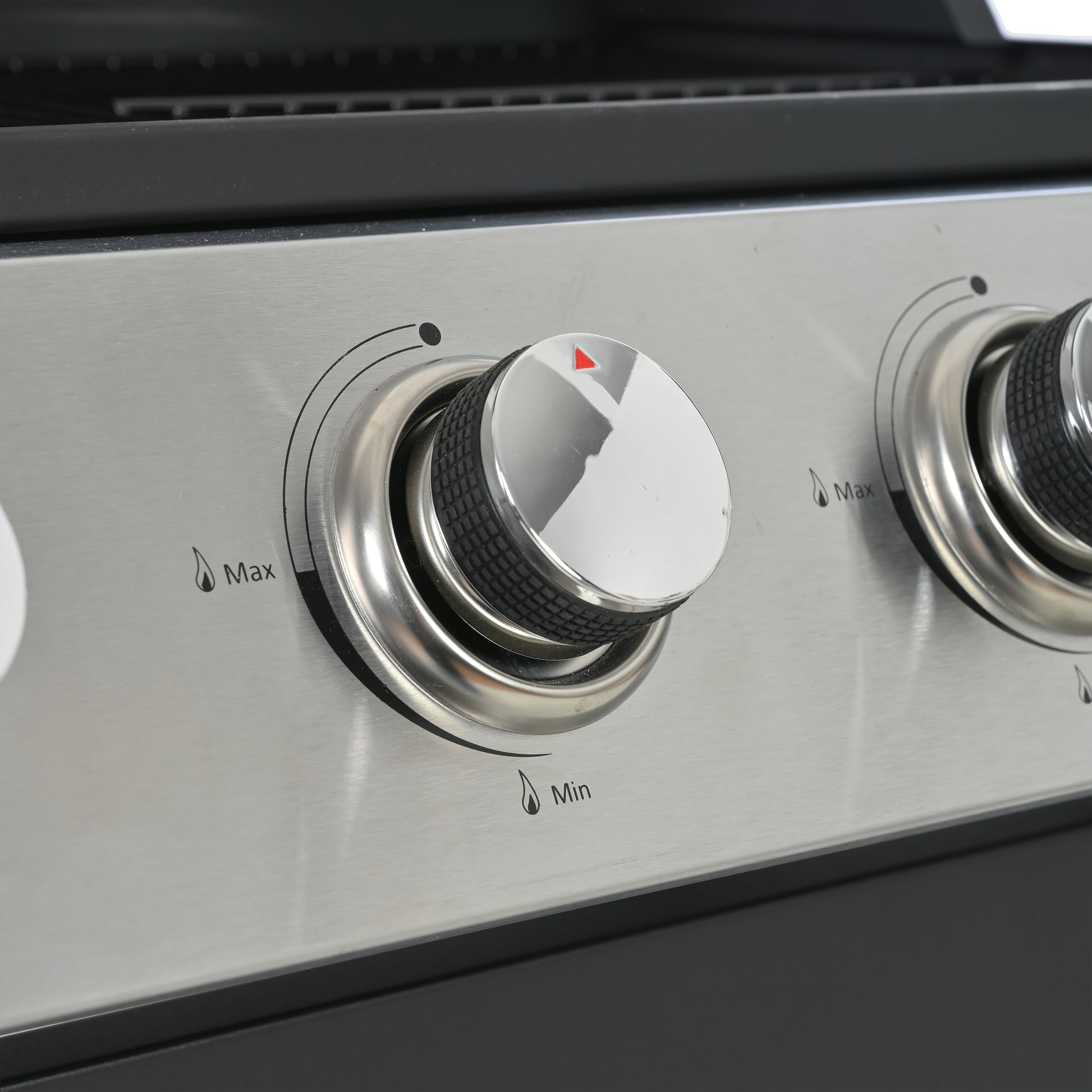 Closeup of a stainless steel grill control knob with red indicator