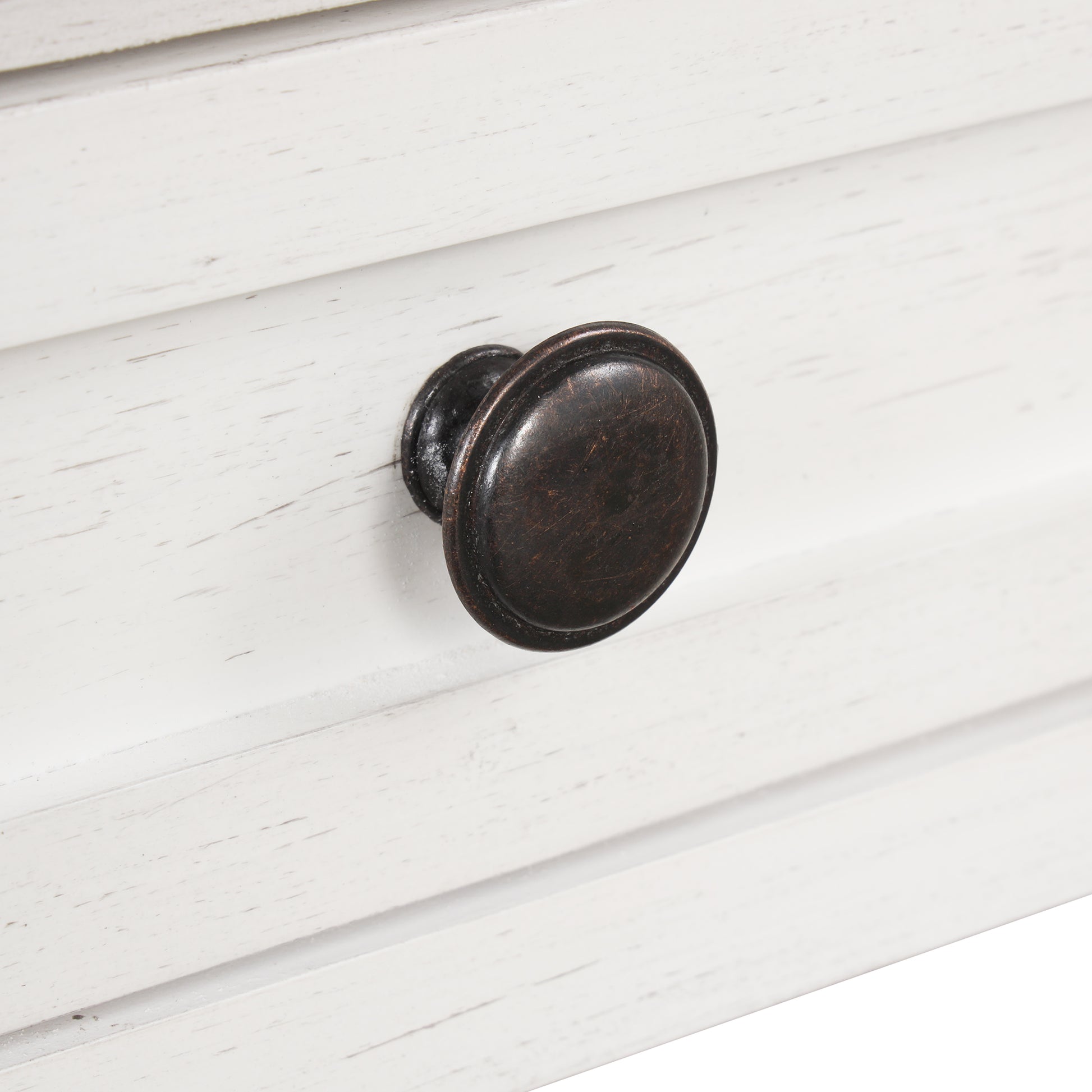 Closeup of antique bronze drawer knob on distressed white dresser drawer