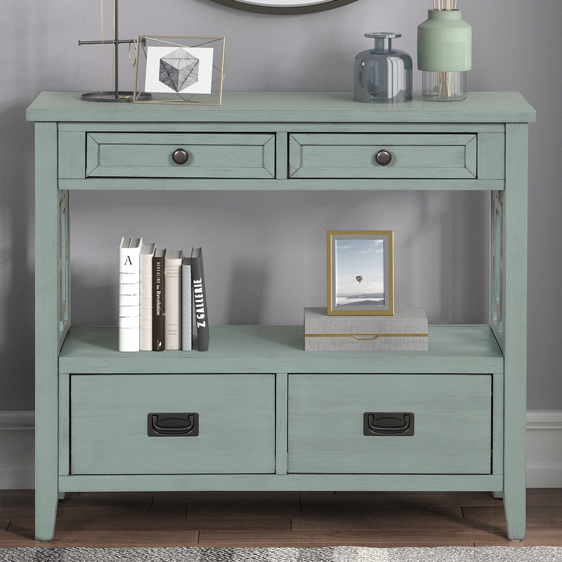 Distressed teal console table with four drawers and open shelf displaying books and decor
