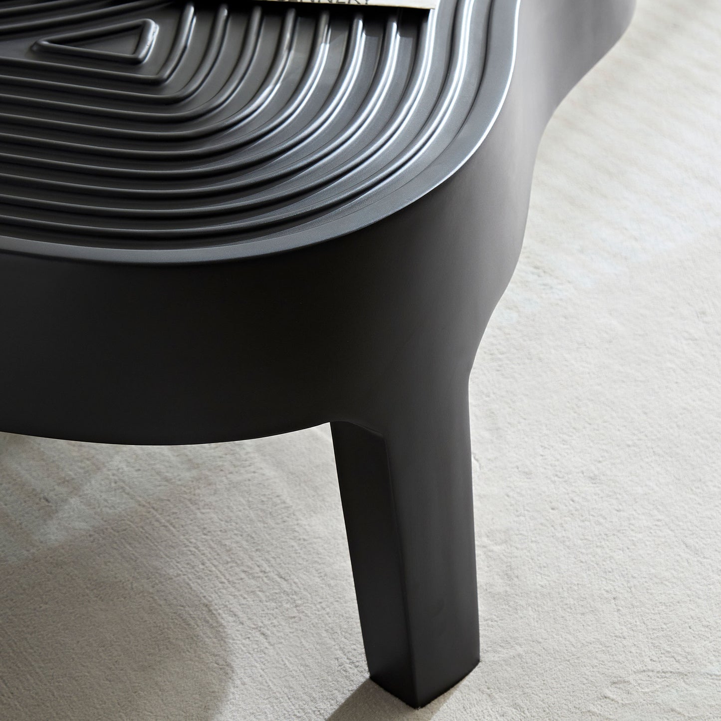 Modern black side table with a textured contoured surface and a minimalist design