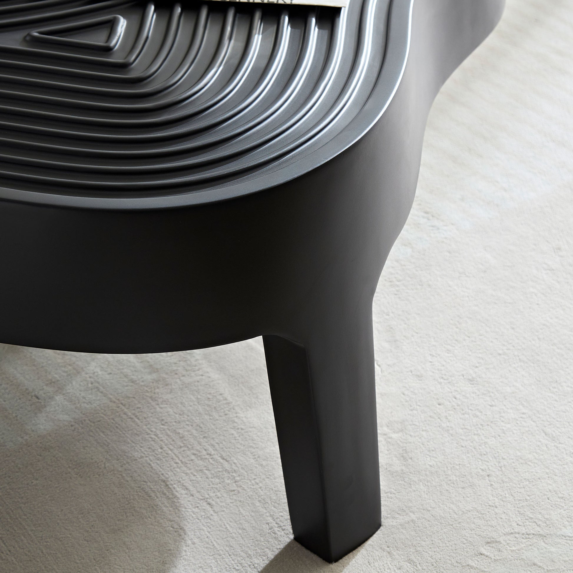 Modern black side table with a textured contoured surface and a minimalist design