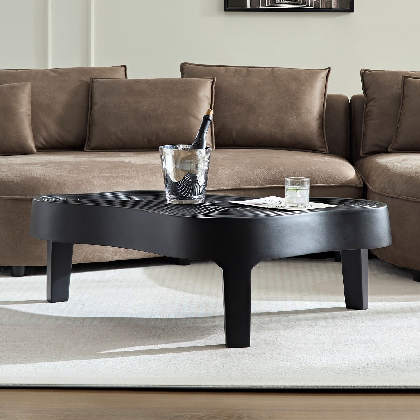 Black modern coffee table with wavy top and tapered legs perfect for living rooms