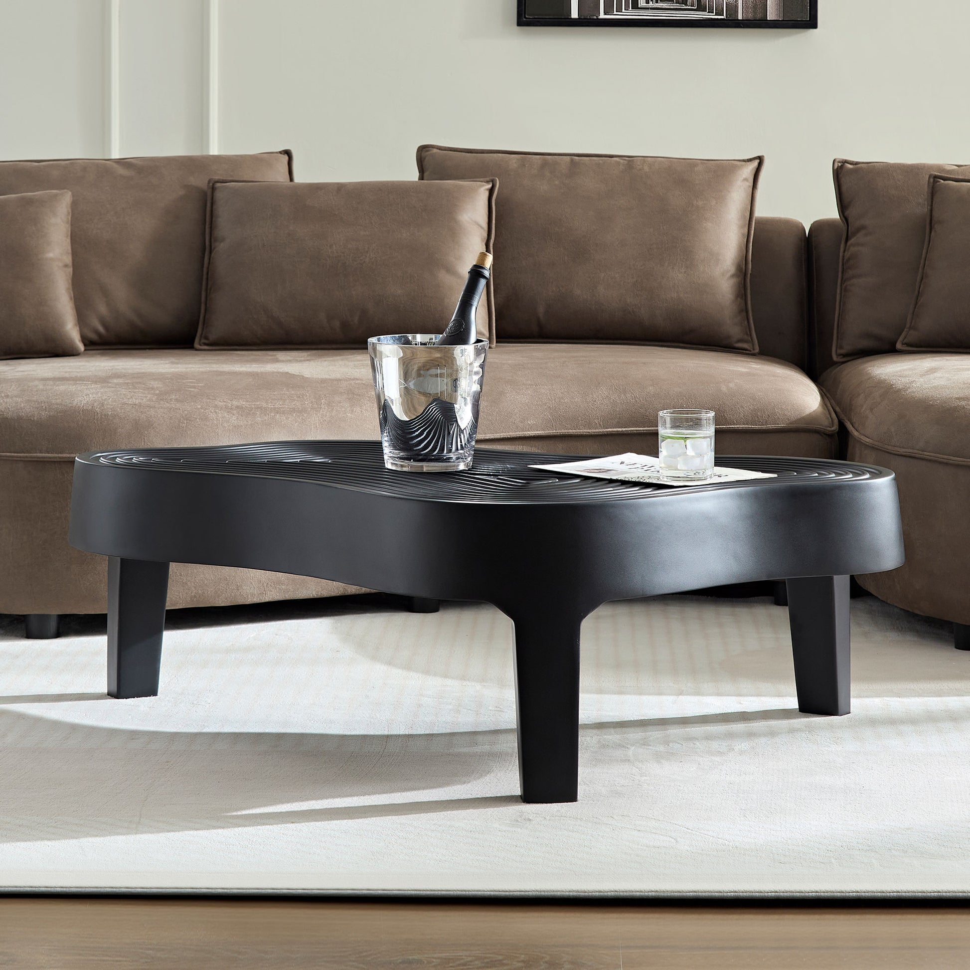 Black modern coffee table with wavy top and tapered legs perfect for living rooms